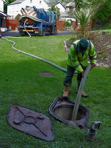 Equipe profissional da Desentupidora Cambuí realizando limpeza de fossa