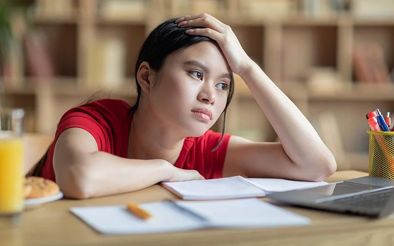 Tired teenager resting on desk during a study session.