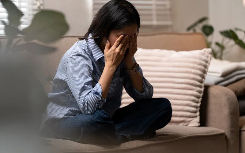 Frustrated woman crying on a sofa after an argument.