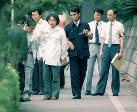 Miyazaki being lead down a road.