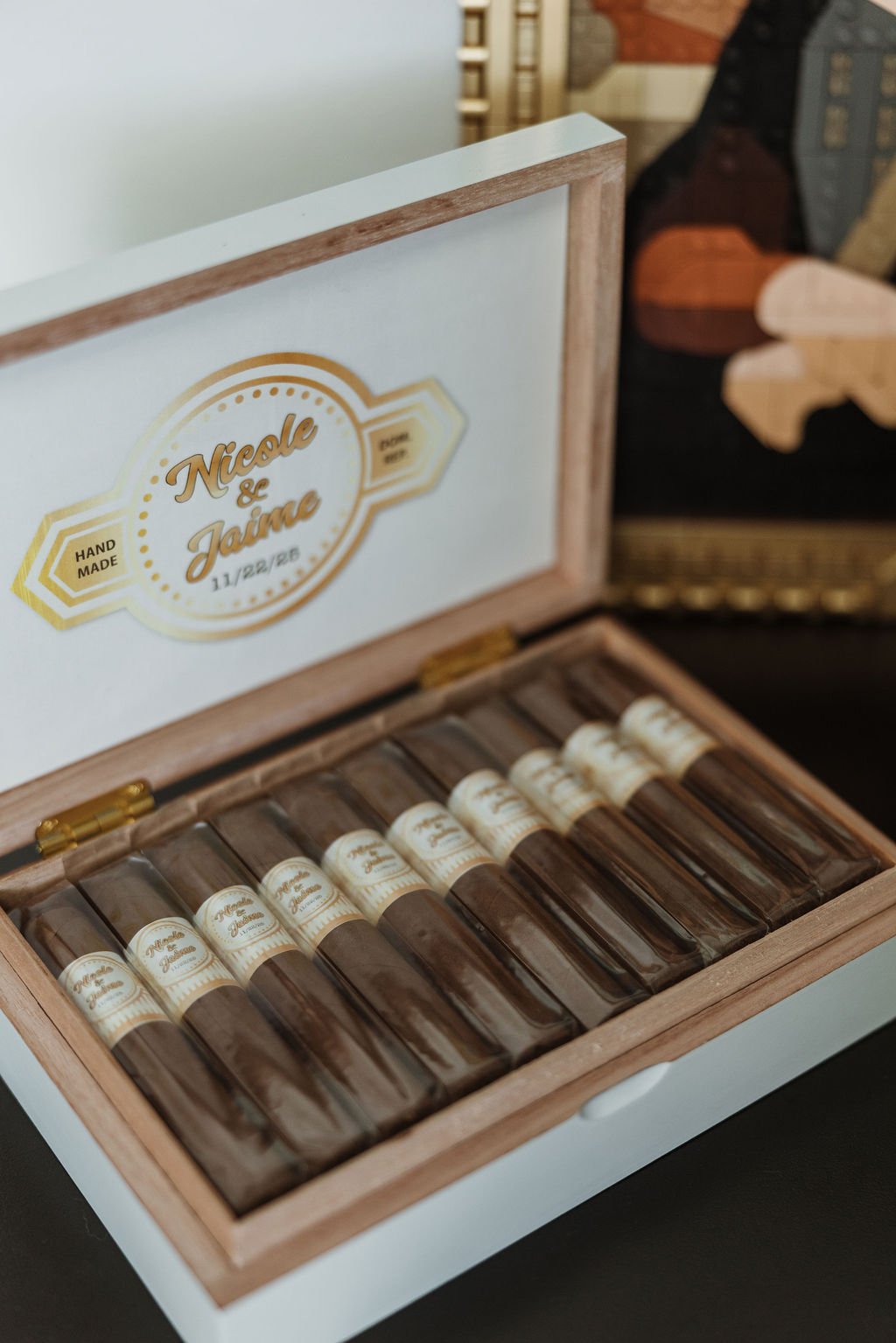 A wooden box containing small glass vials with labels reading 'Nicole & Jaime' and a date, 11/22/22. The box is open, displaying the vials inside.