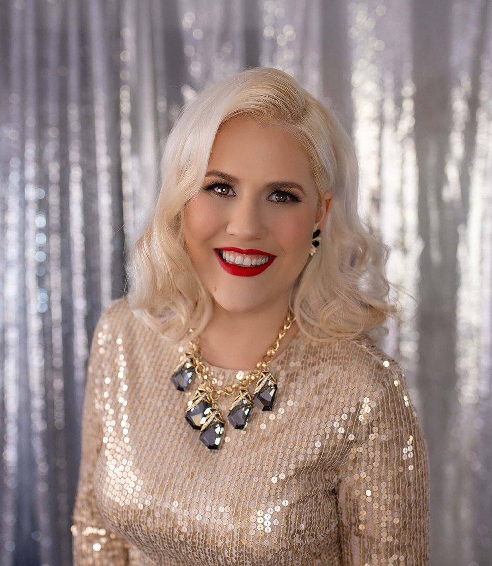 beautiful blond woman with hazel eyes in a gold sequin dress smiles at the camera
