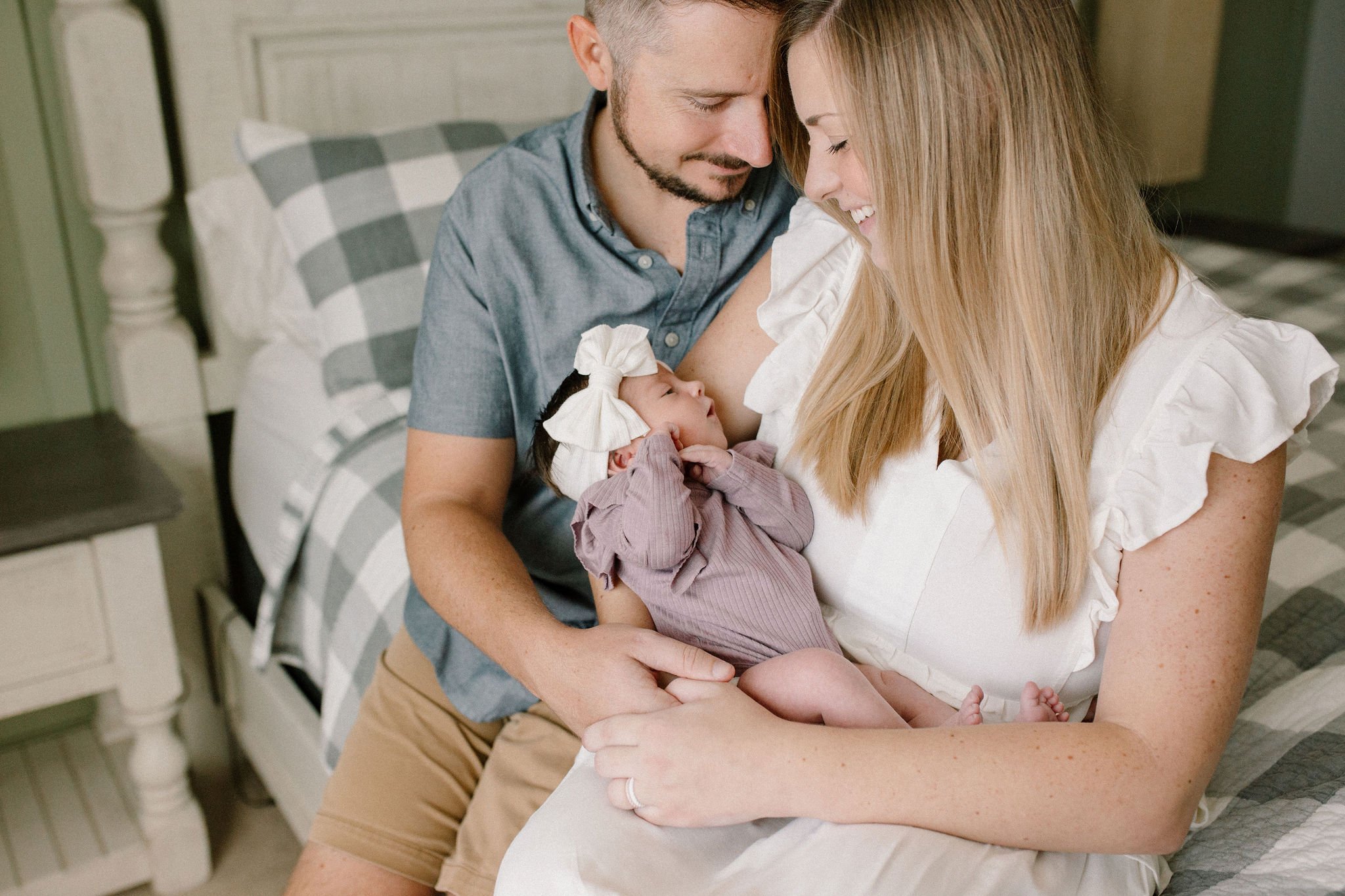 Mom and dad holding baby on bed with Mesa newborn photographer