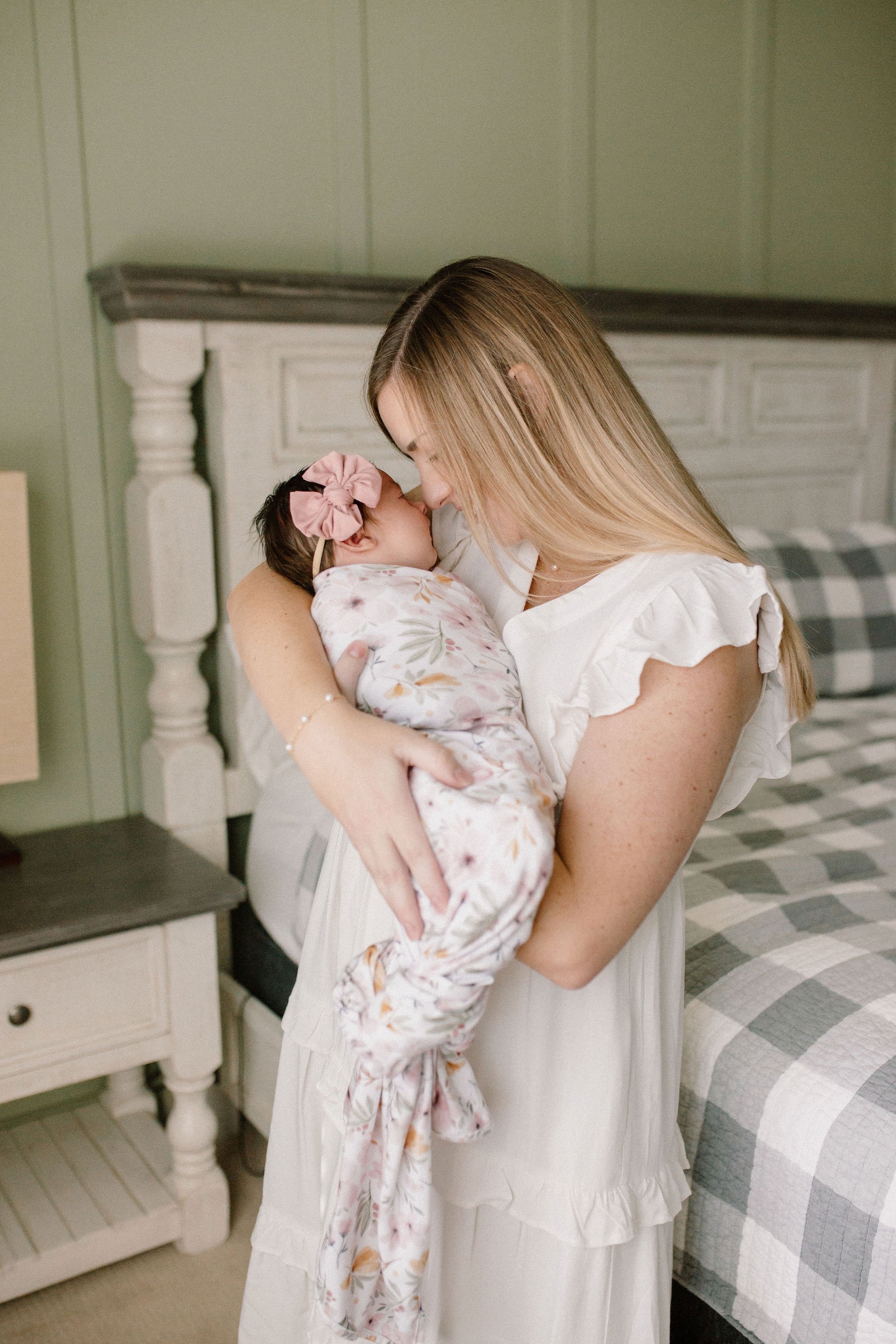 mom holding baby girl in primary bedroom window light by Mesa newborn photographer