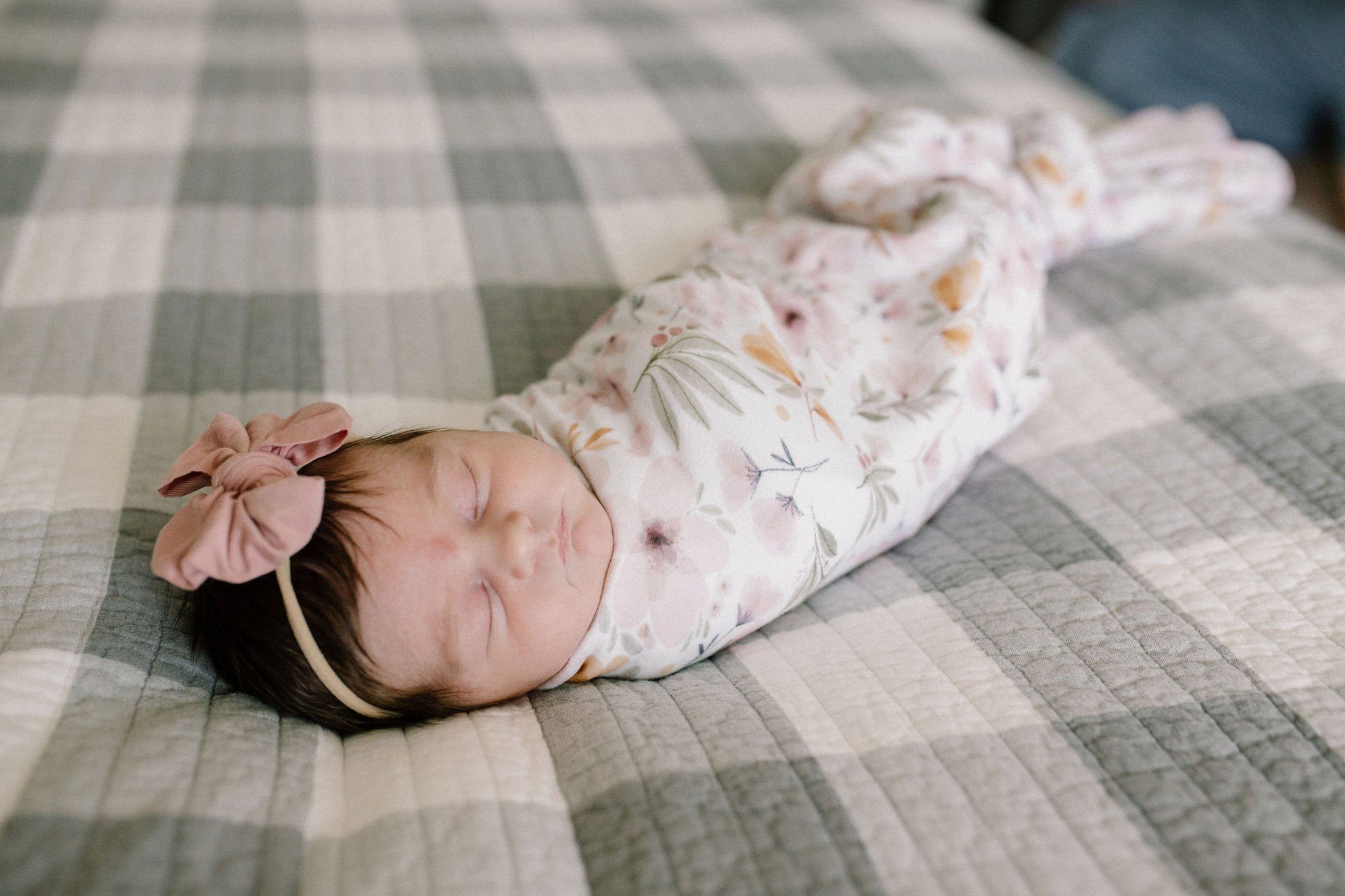 swaddled baby sleeping on bed captured by Mesa newborn photographer