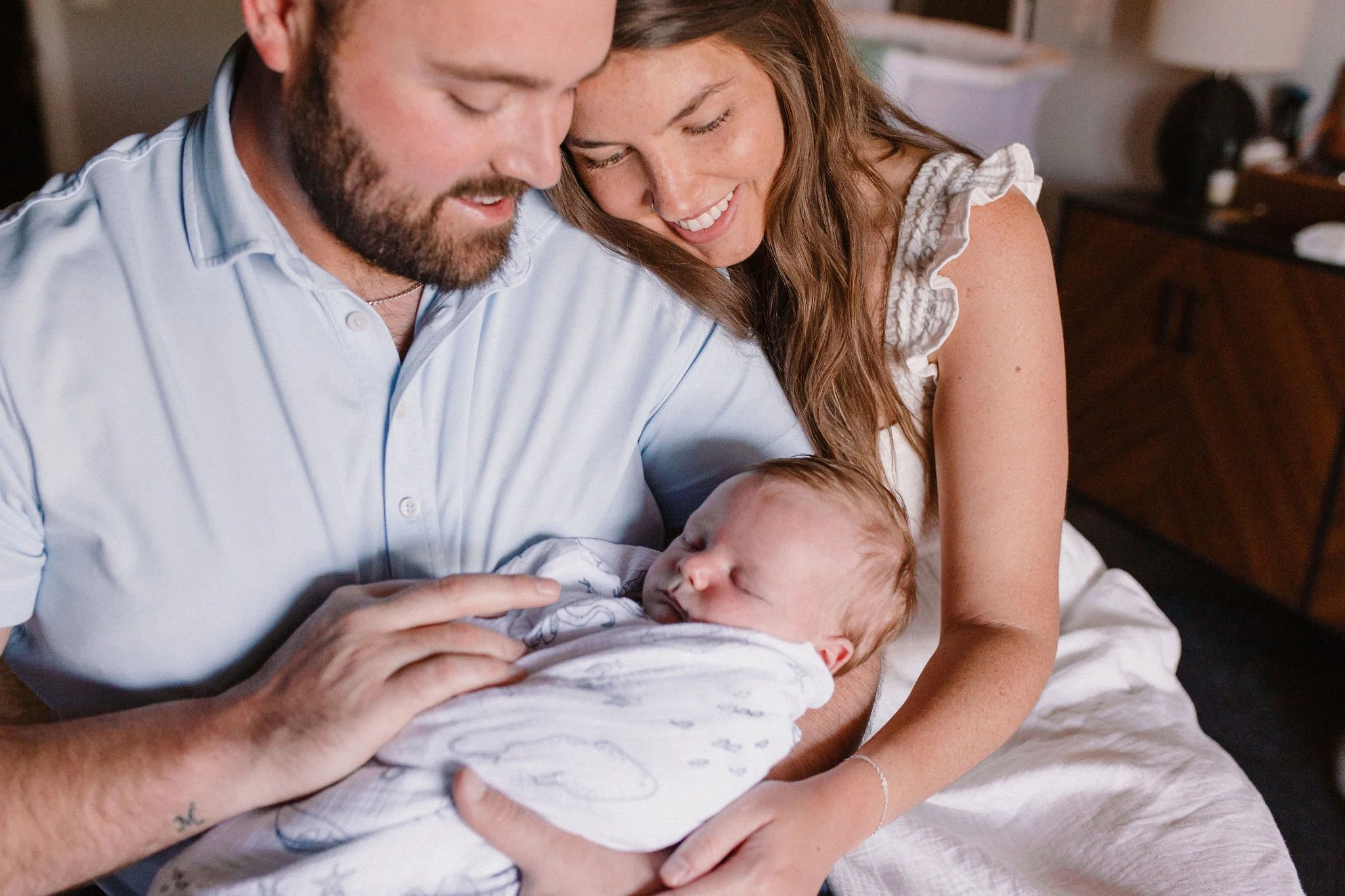 dad holding swaddled baby with mom cuddling on his shoulder captured by Tempe Arizona newborn photographer