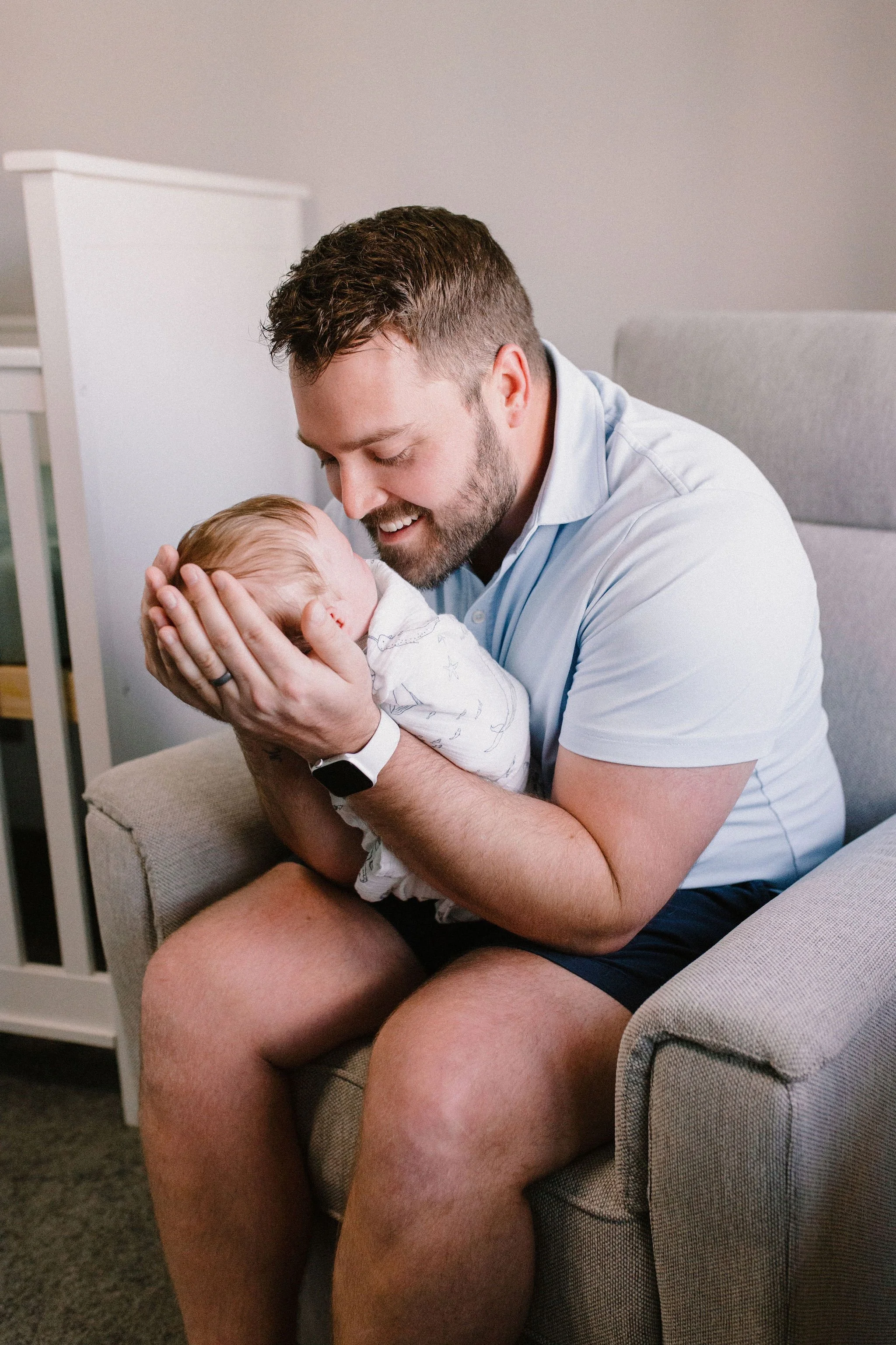 dad holding baby in rocking chair in nursery captured by Tempe Arizona newborn photographer