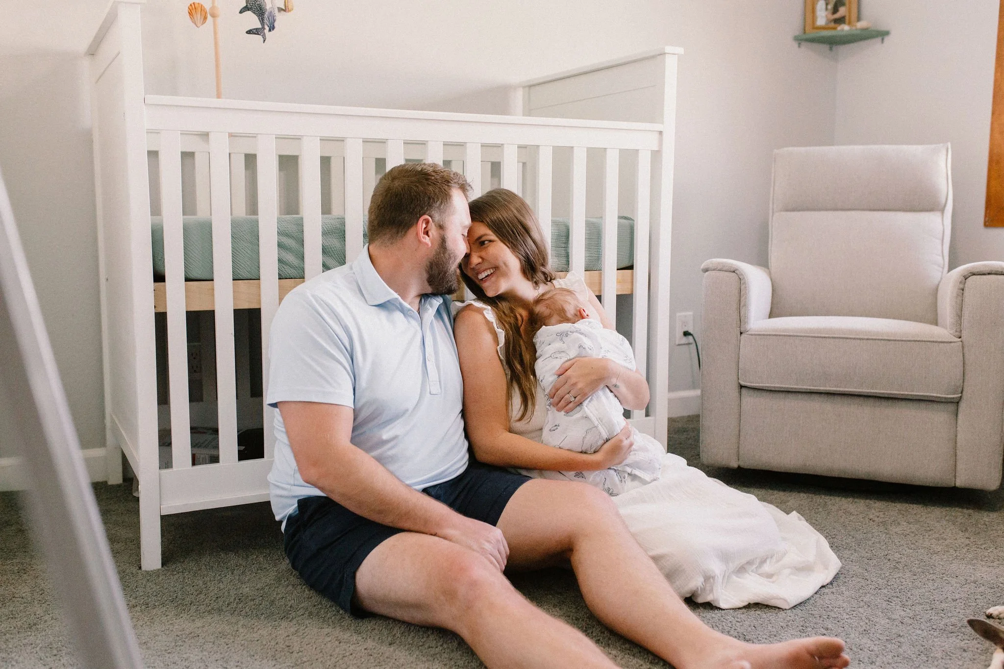 Mom and dad holding baby in nursery by crib taken by Tempe Arizona newborn photographer