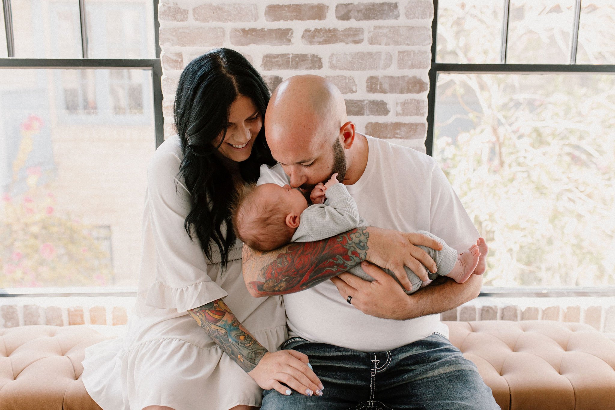 mom and dad holding baby in natural light studio by Phoenix newborn photographer