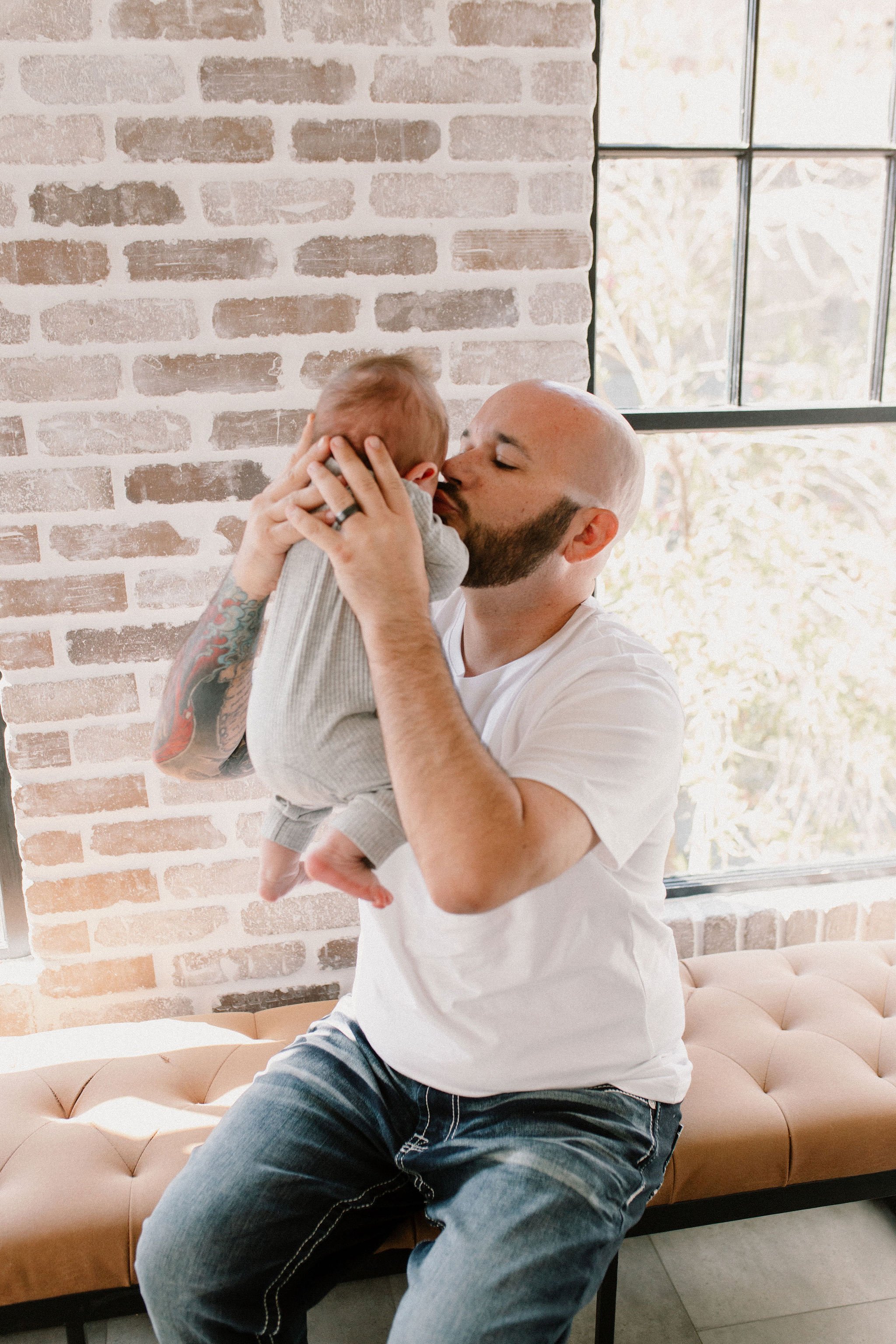 dad kissing baby in natural light studio by Phoenix newborn photographer