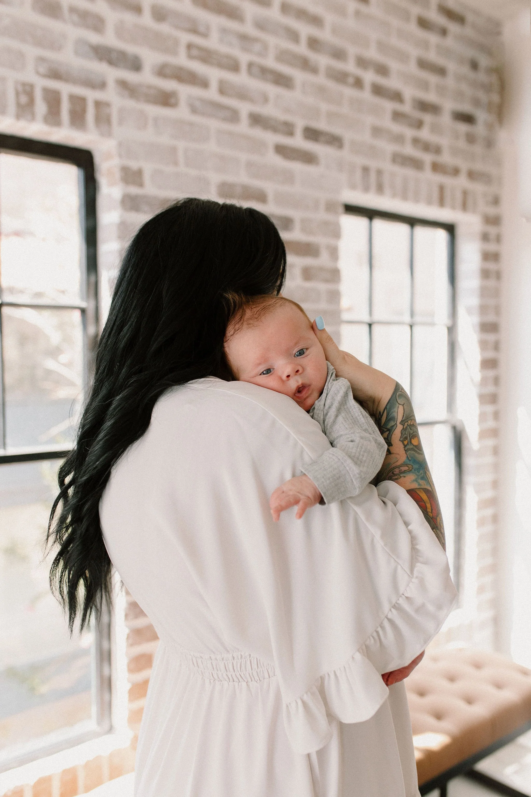 mom holding baby in natural light studio with phoenix newborn photographer