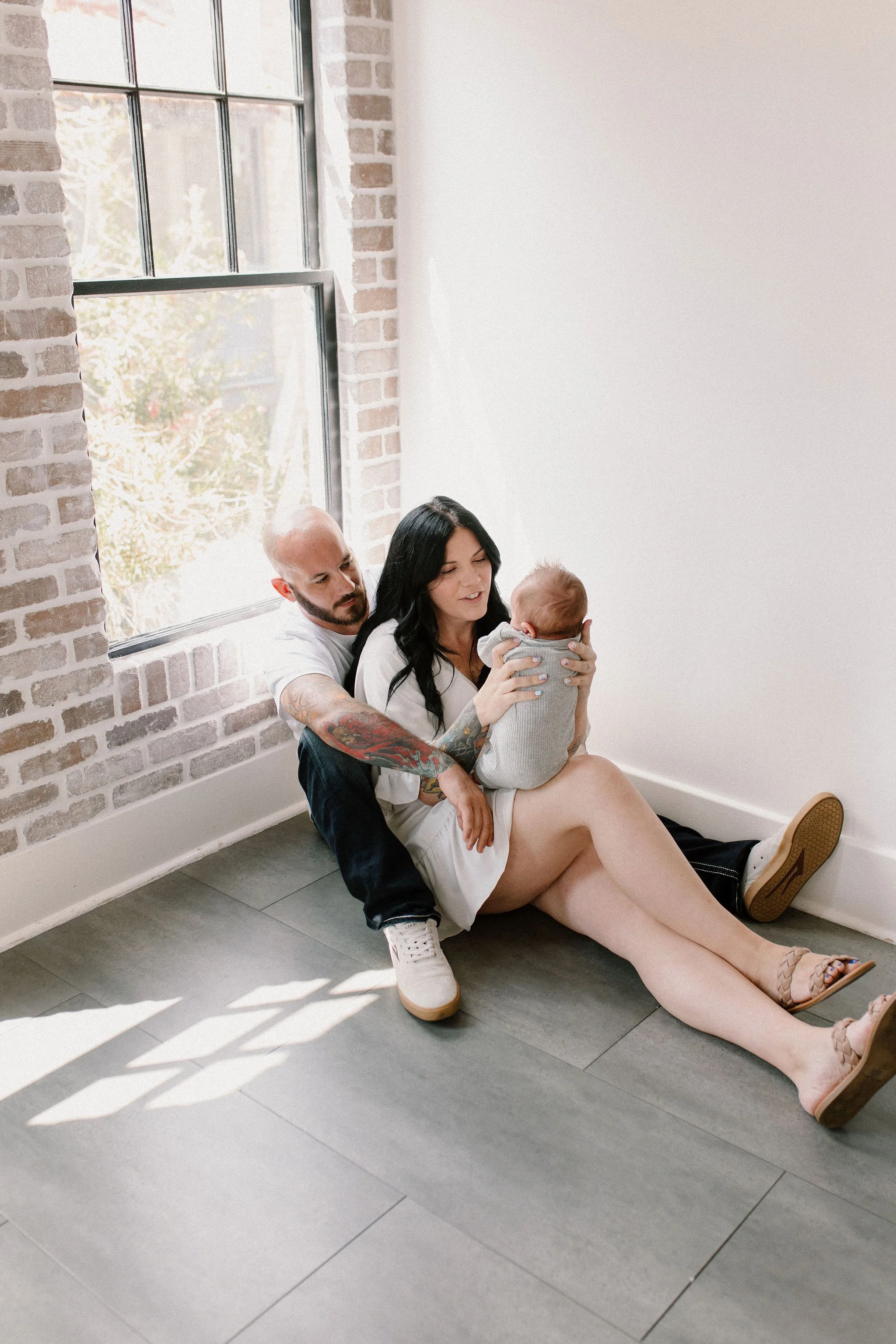 phoenix newborn photographer captures mom and dad holding newborn baby in neutral natural light studio session