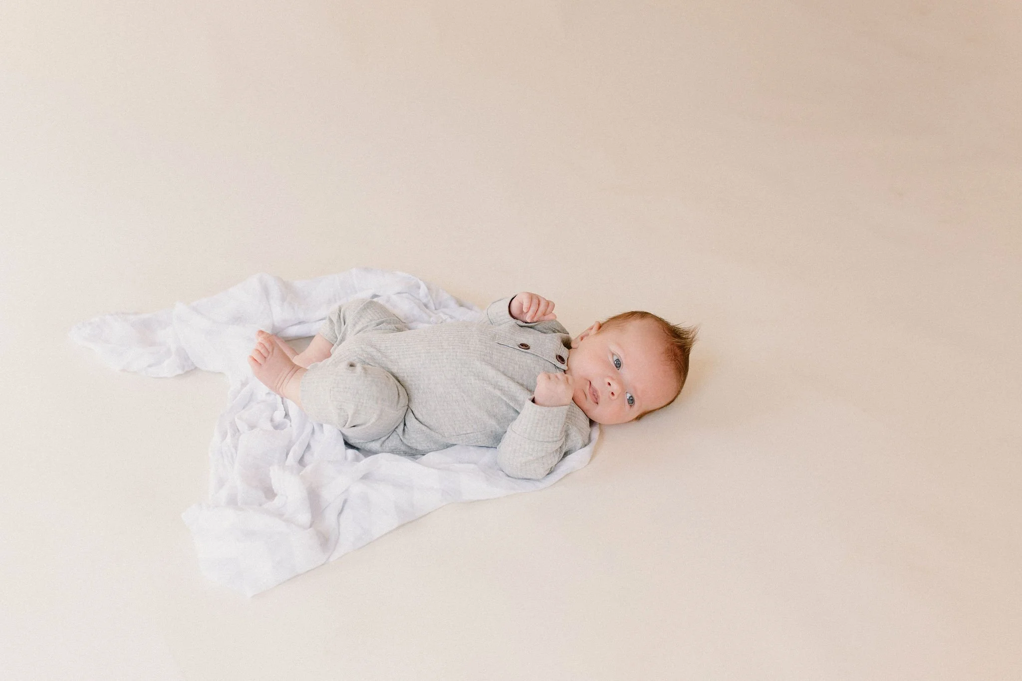 baby laying on swaddle in neutral natural light studio by Phoenix newborn photographer