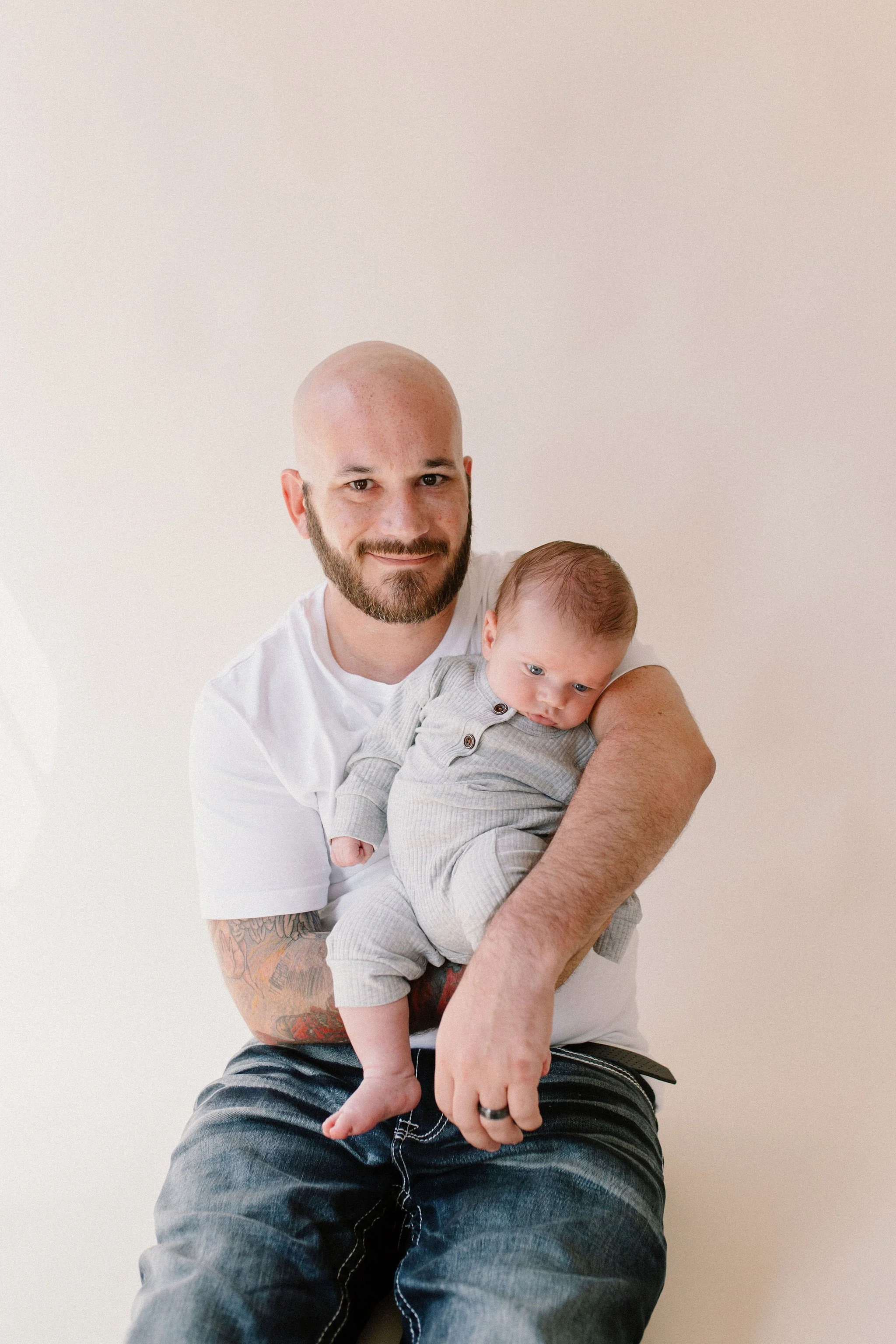 dad holding baby in neutral natural light studio by Phoenix newborn photographer