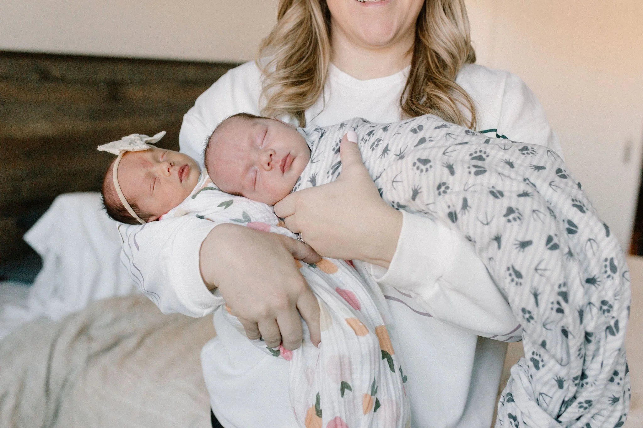 mom holding swaddled newborn baby twins