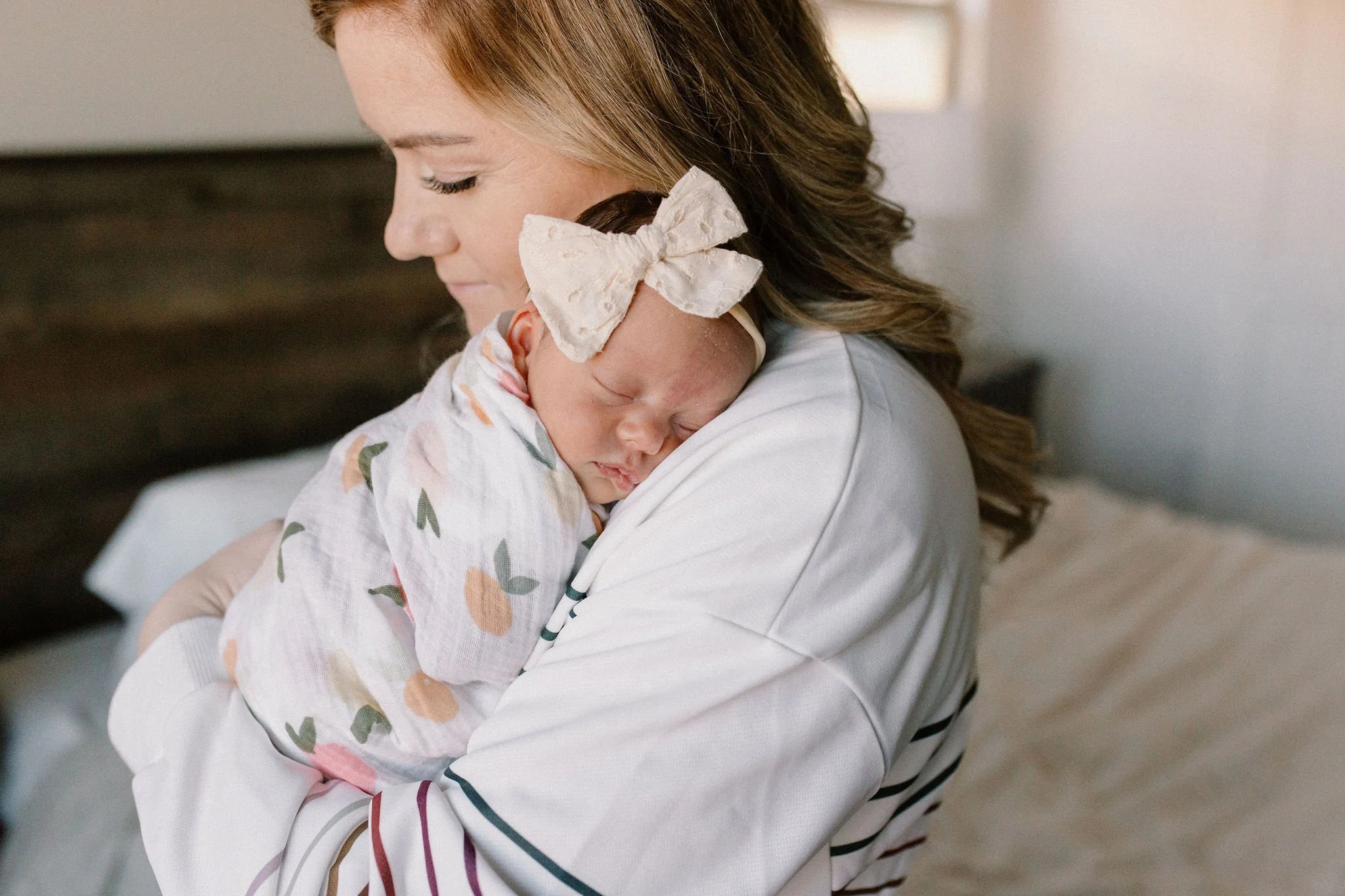 mom holding swaddled newborn baby girl