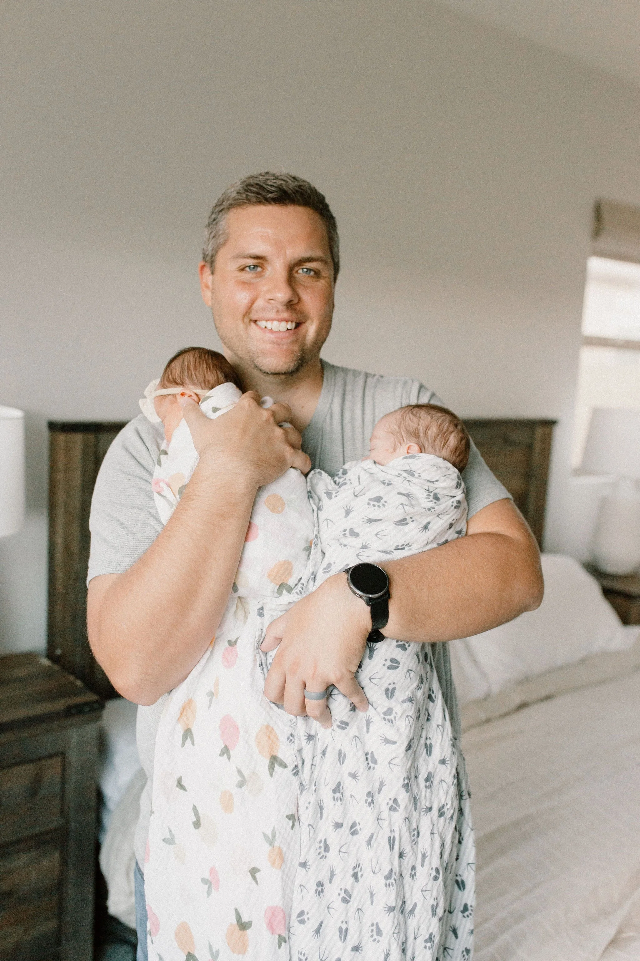 dad holding swaddled newborn baby twins