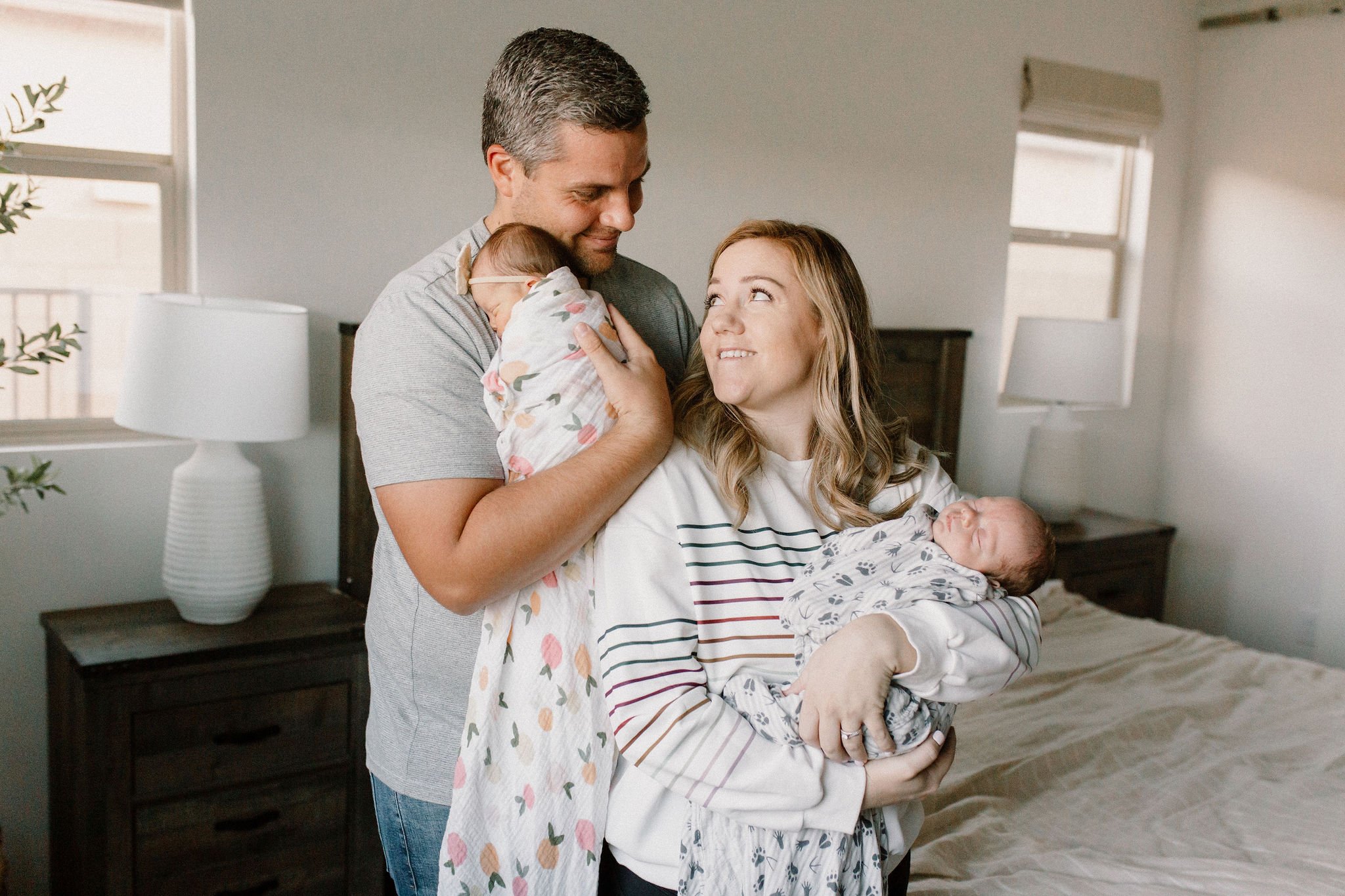 mom and dad holding swaddled newborn baby twins