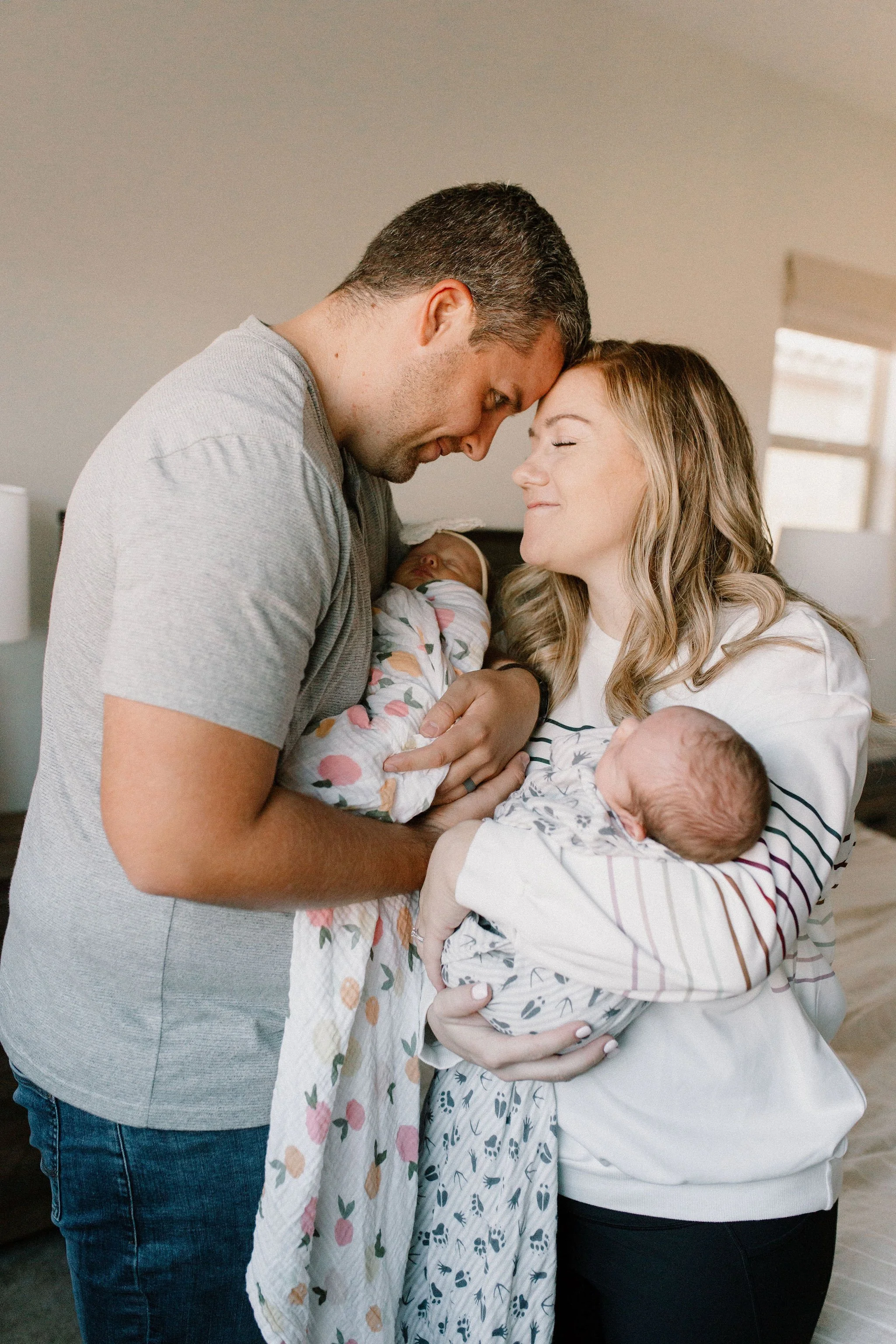mom and dad holding swaddled newborn twins