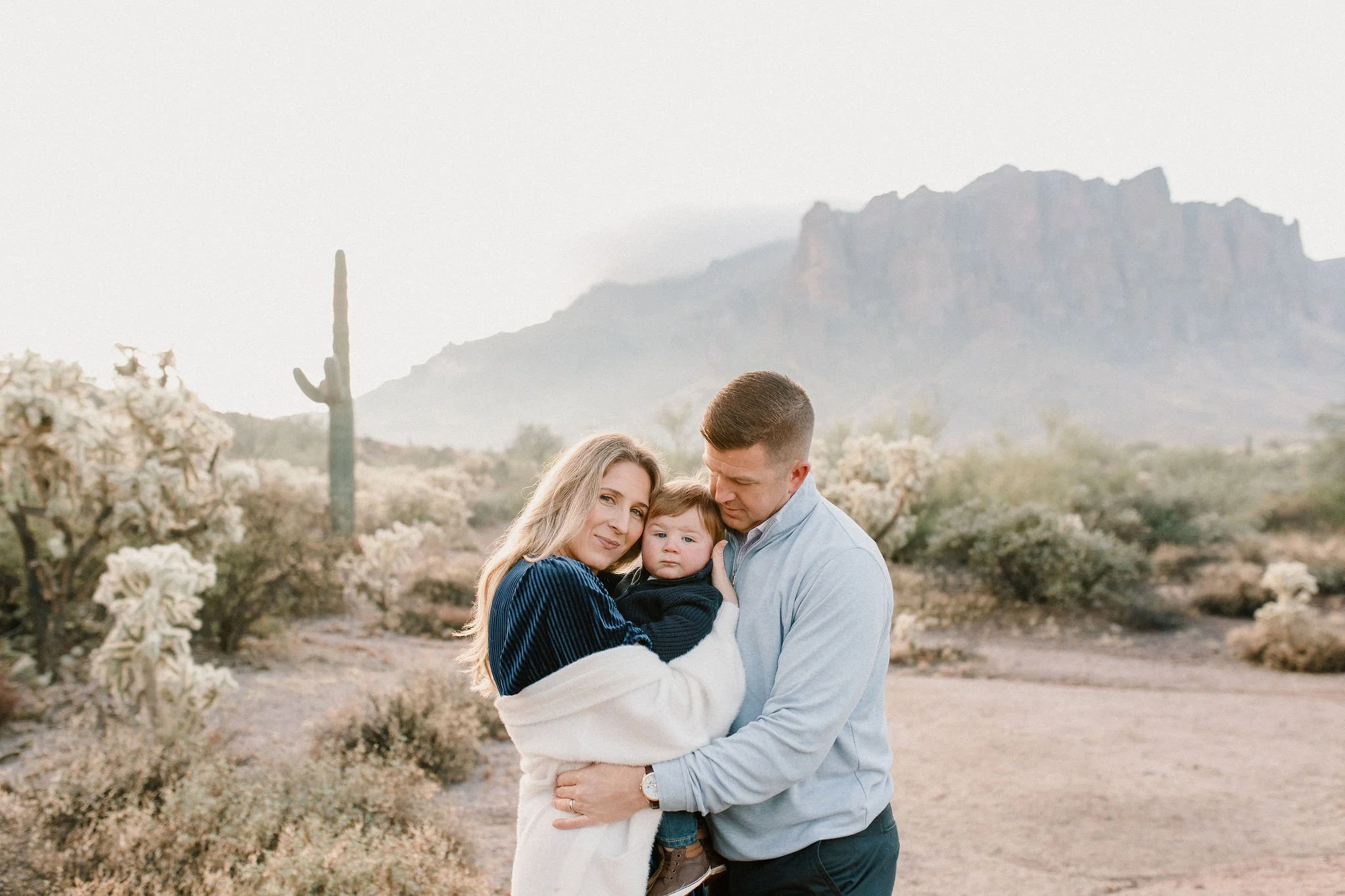 mom and dad cuddling baby boy in misty desert family session at the Superstition Mountains
