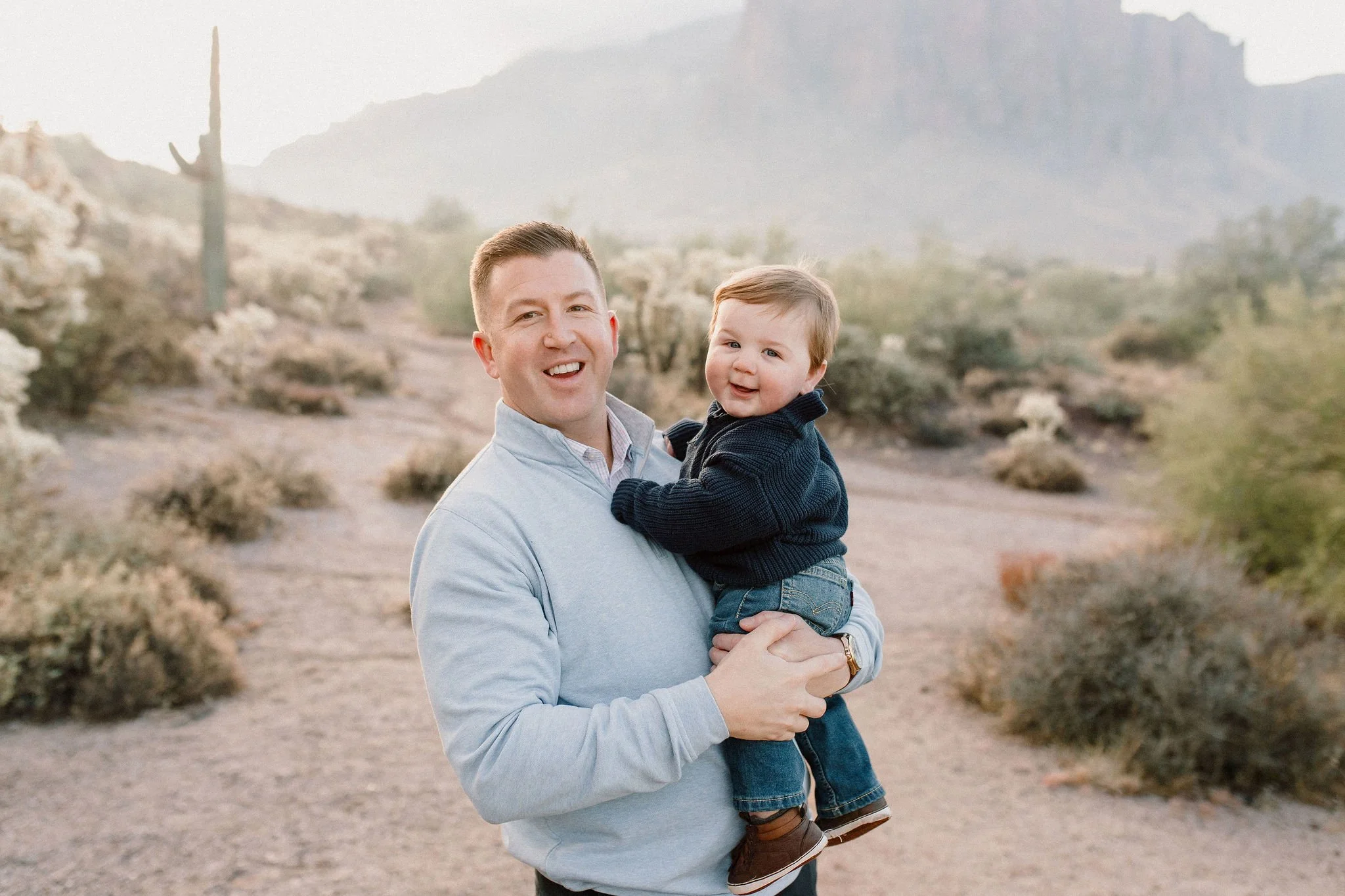 dad and baby boy standing in desert and smiling