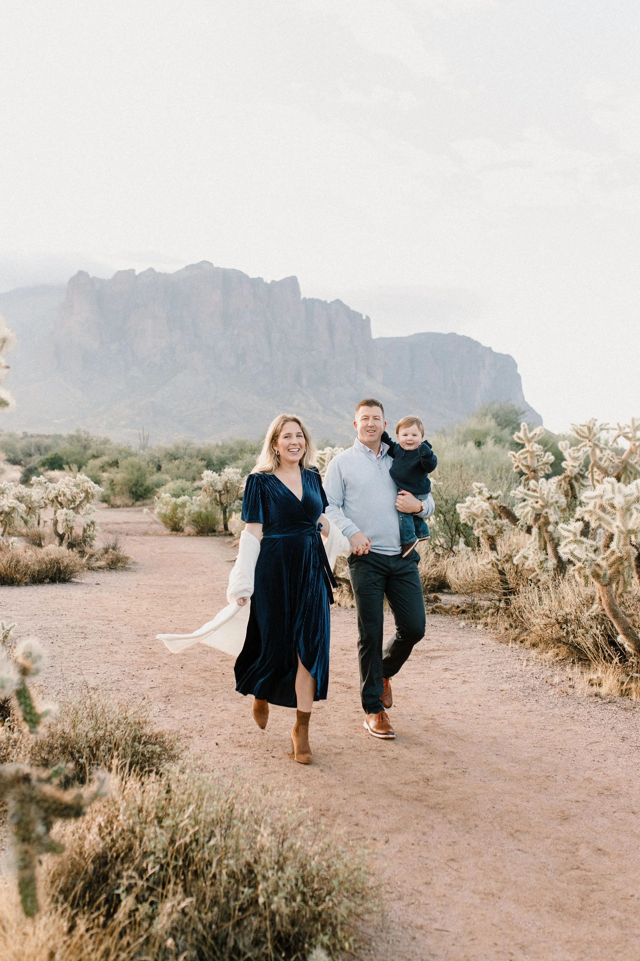 family of three walking together in the desert with misty mountains in the background