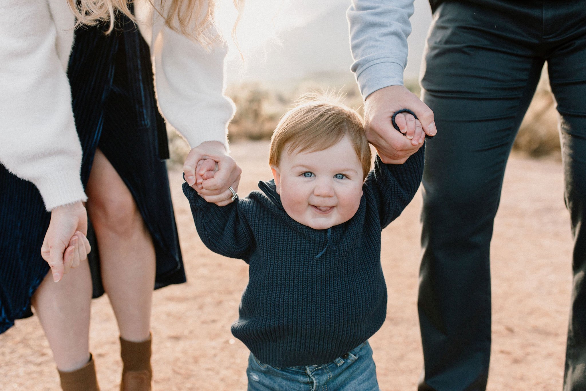 baby boy holding mom and dad's hands walking in the desert during misty morning photography session