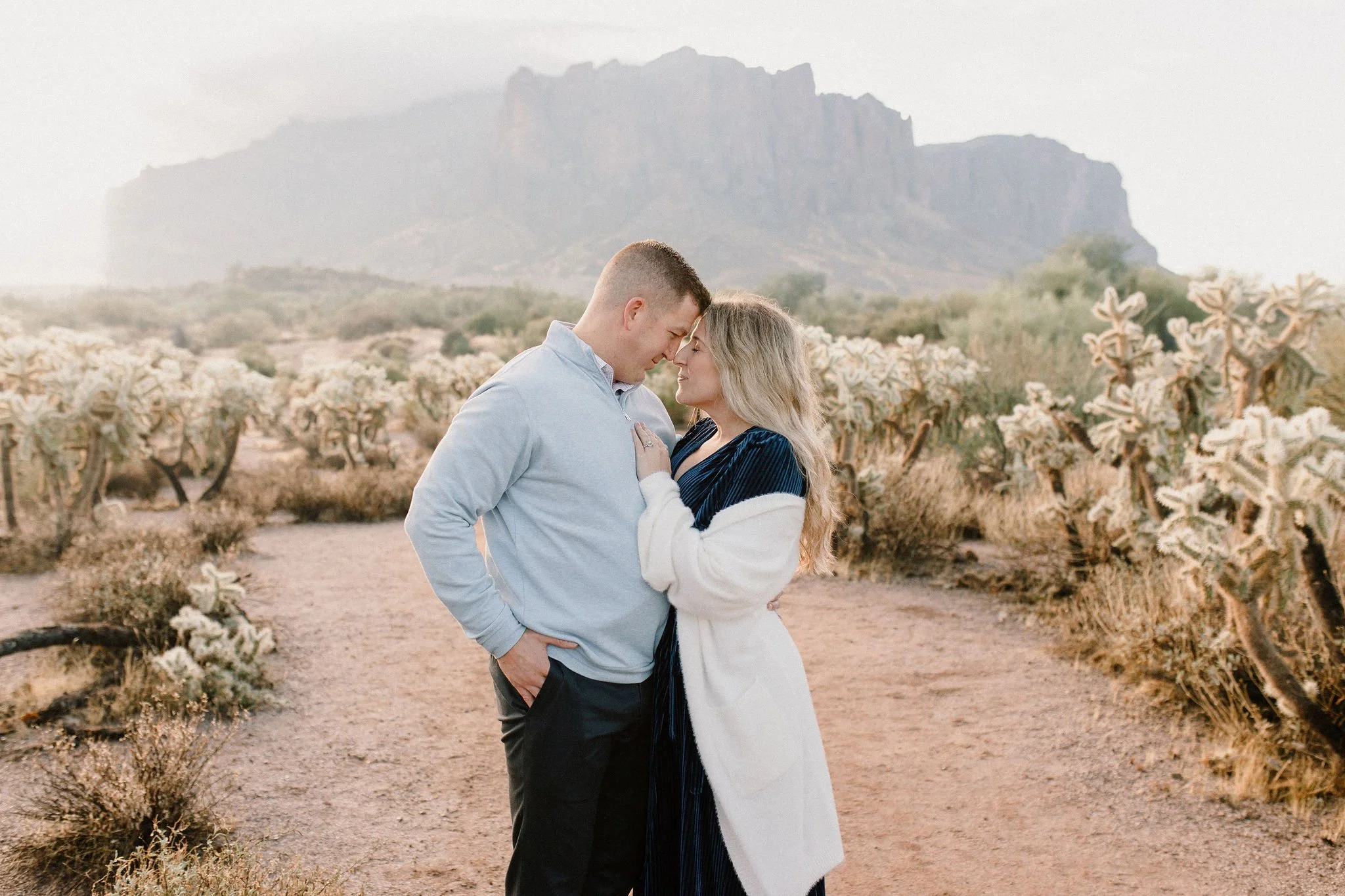 mom and dad cuddling in misty morning desert family photography session at the Superstion Mountains in Arizona