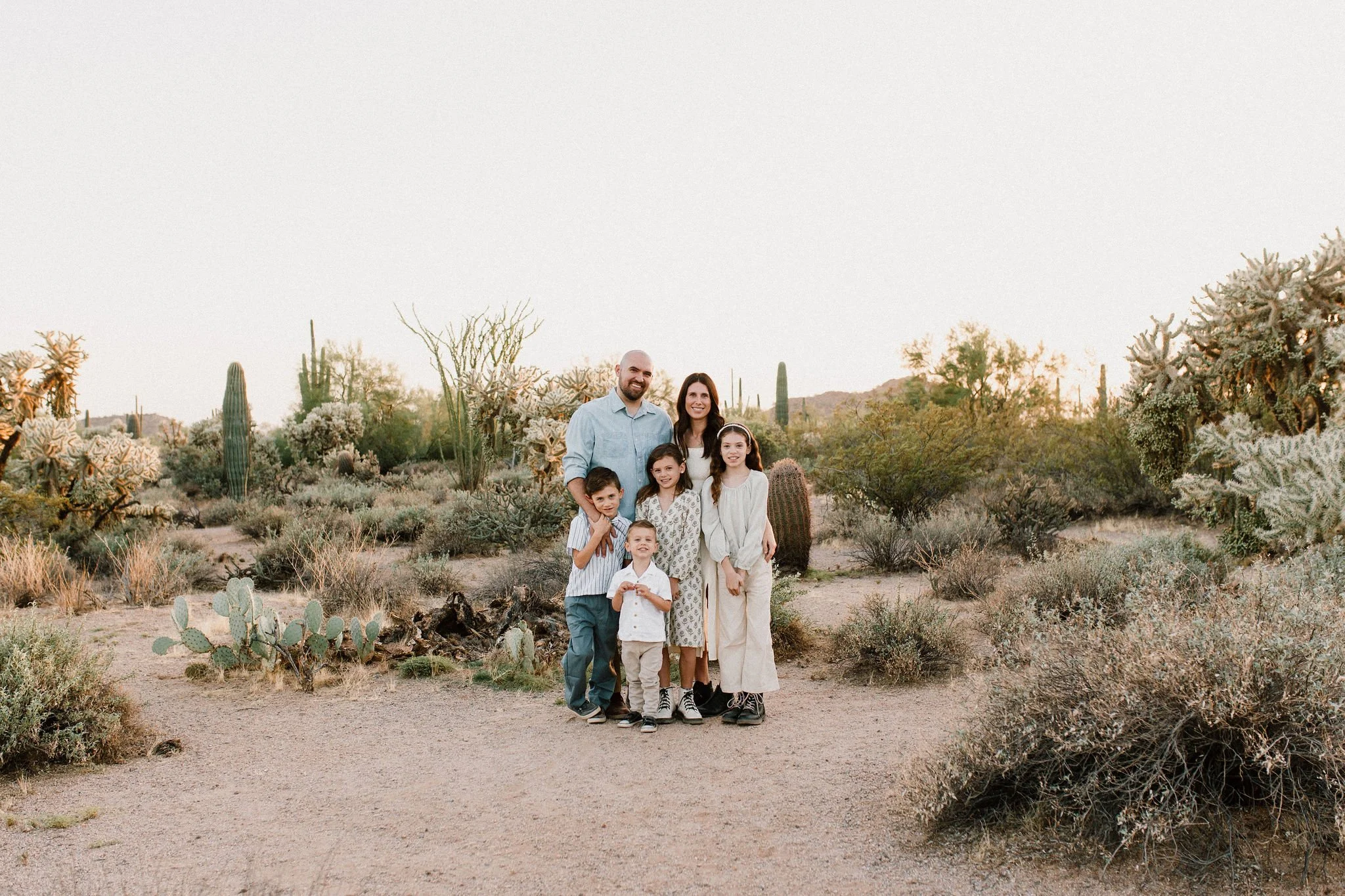 family standing and smiling at Mesa family photographer in Arizona desert