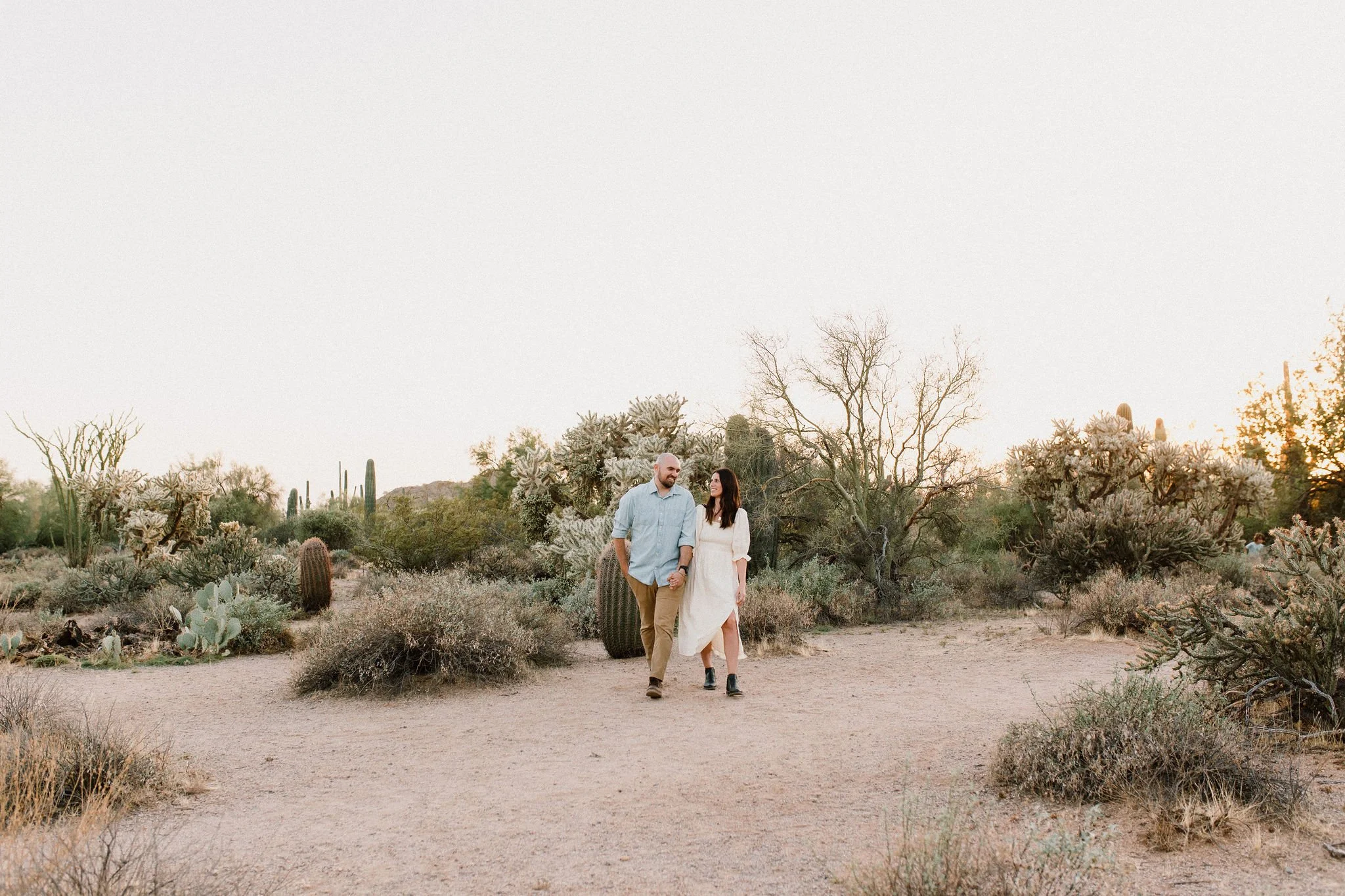 mom and dad walking and holding hands taken by Mesa family photographer in Arizona desert