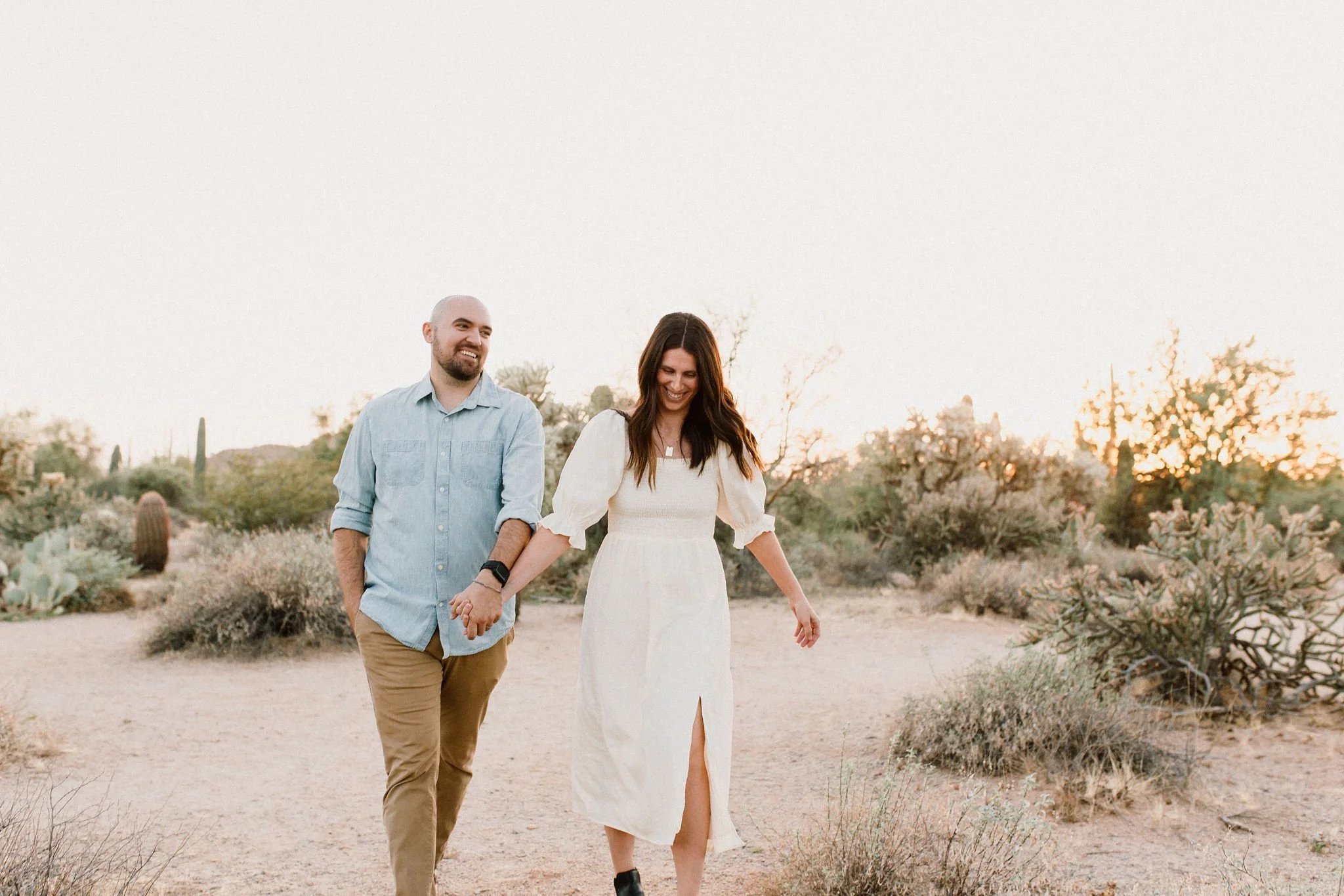 mom and dad walking and holding hands captured by Mesa family photographer in Arizona desert