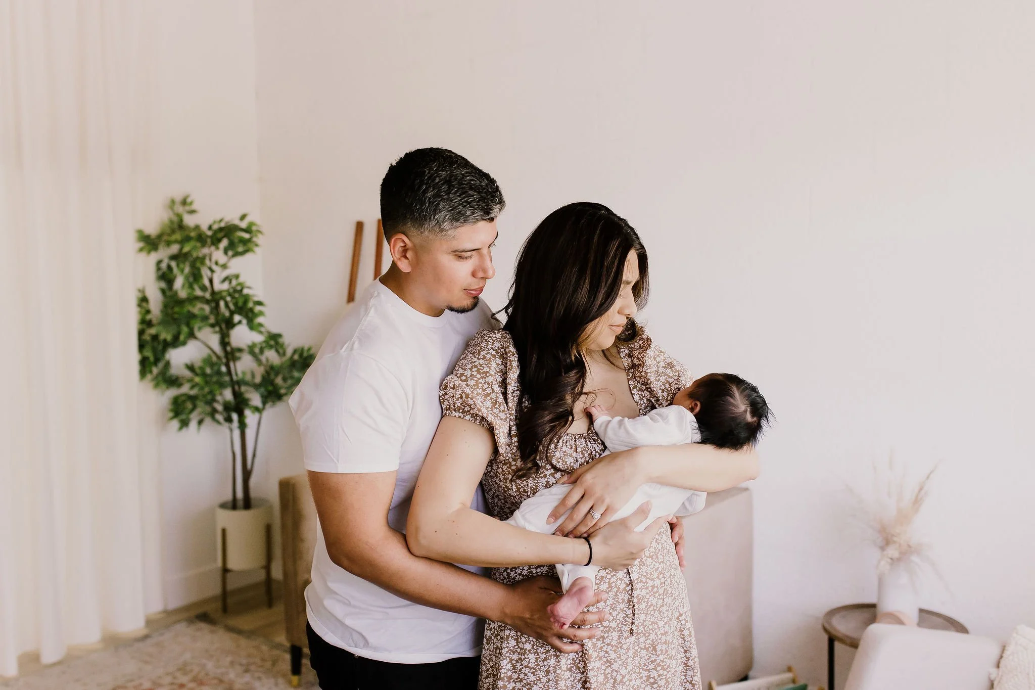 mom holding baby with dad cuddling close in nursery for studio newborn photography session