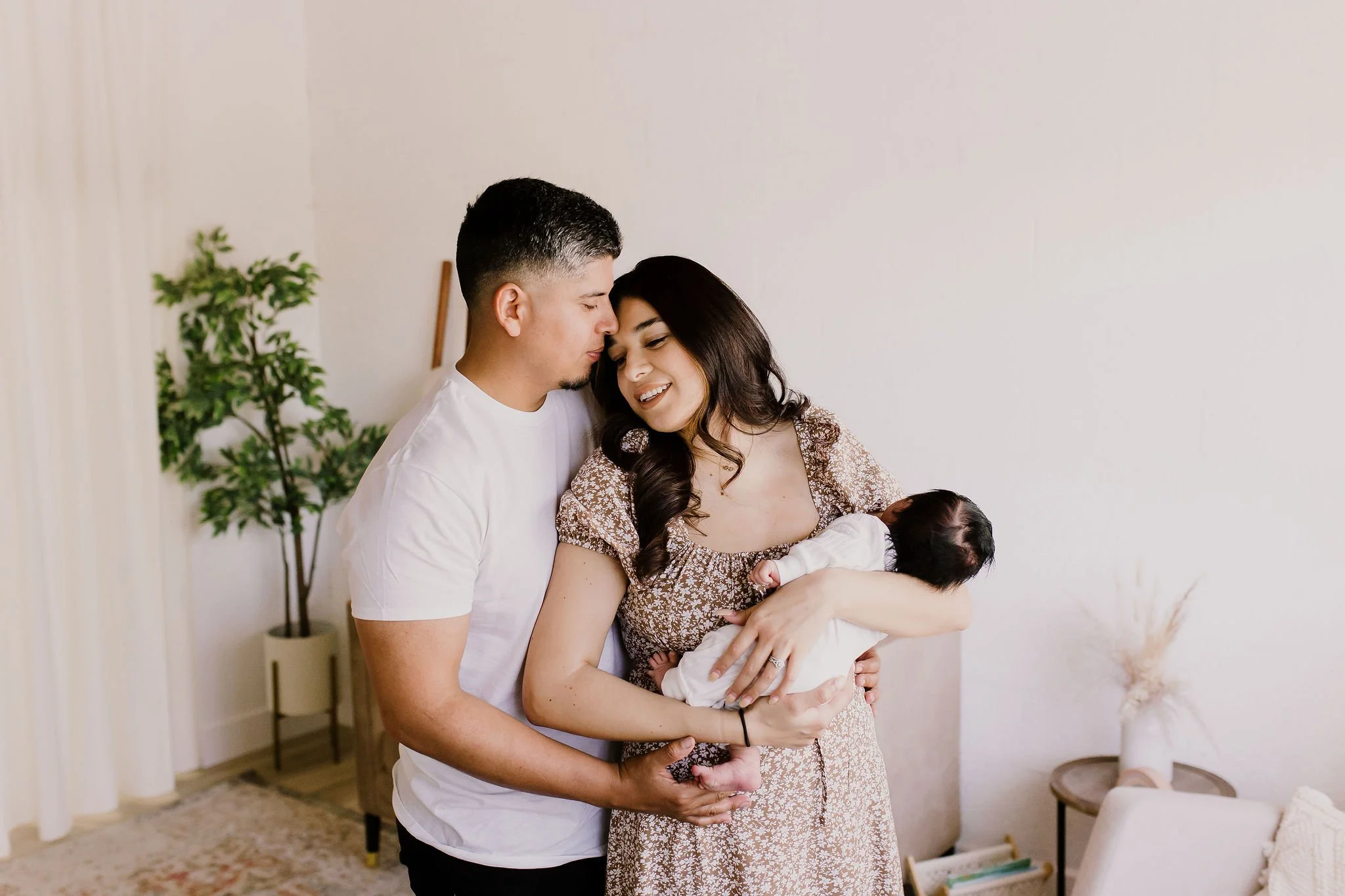 mom holding baby with dad cuddling close in nursery for studio newborn photography session