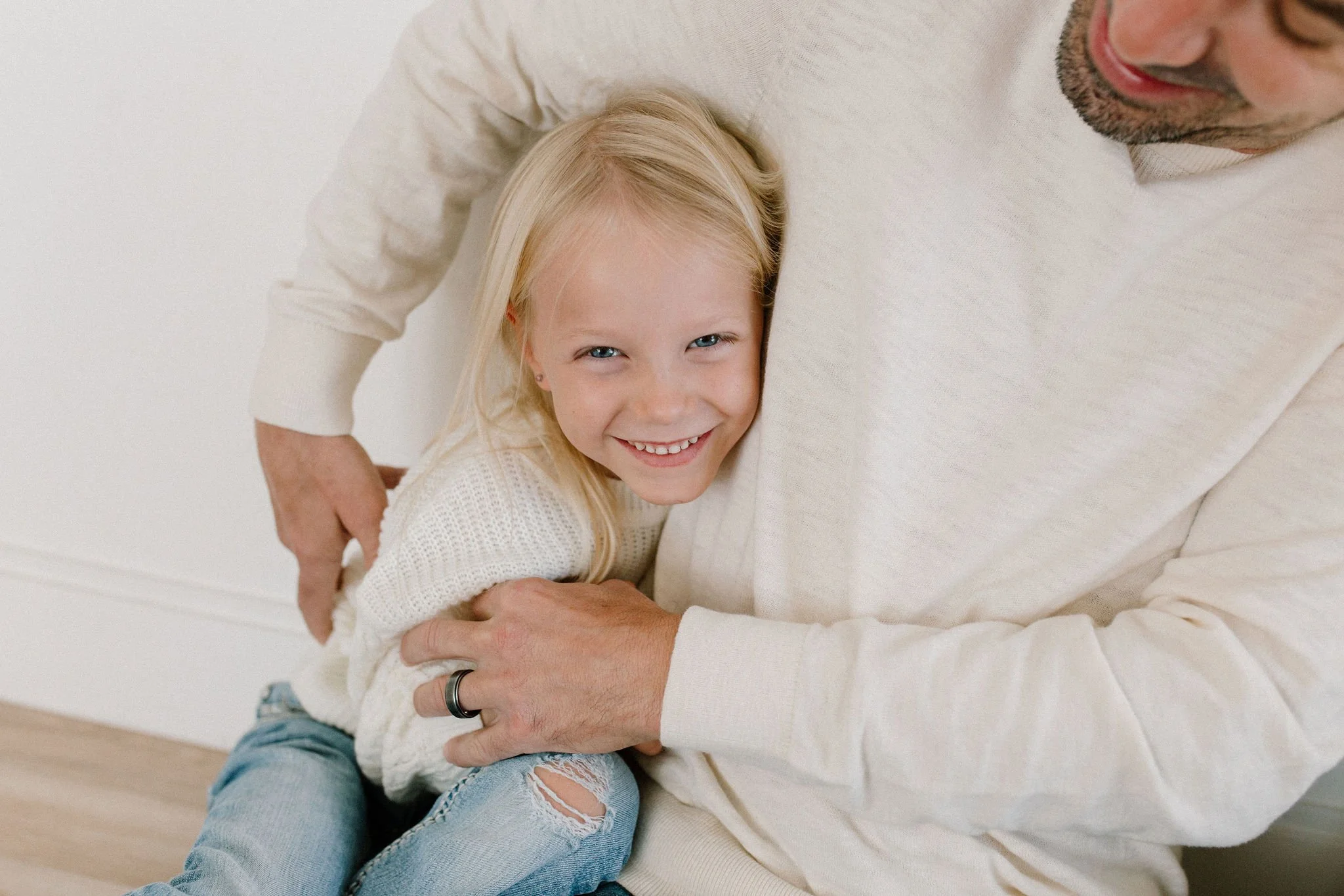 dad tickling daughter in neutral studio space