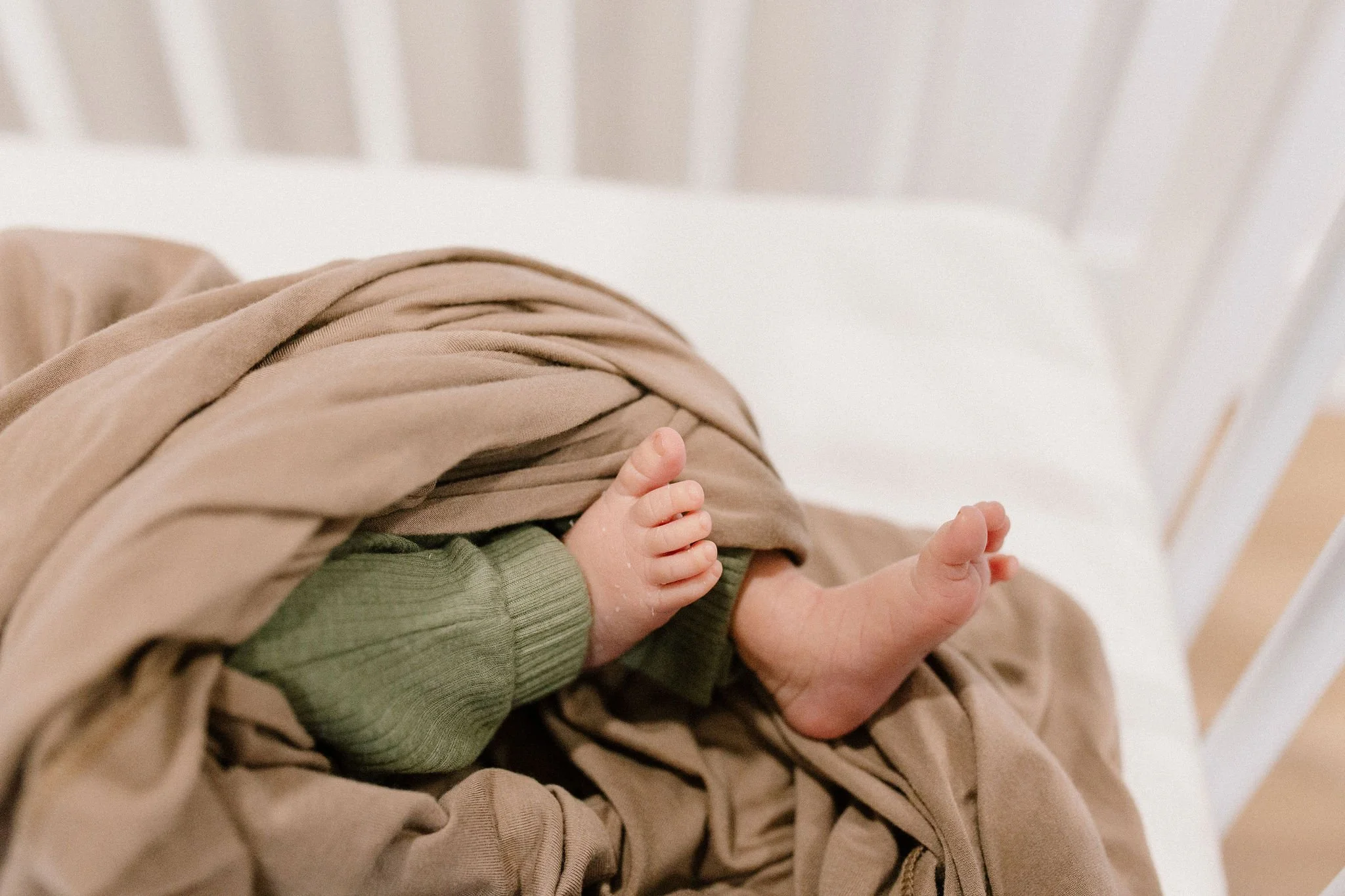 close-up photo of newborn baby toes in neutral nursery bassinet