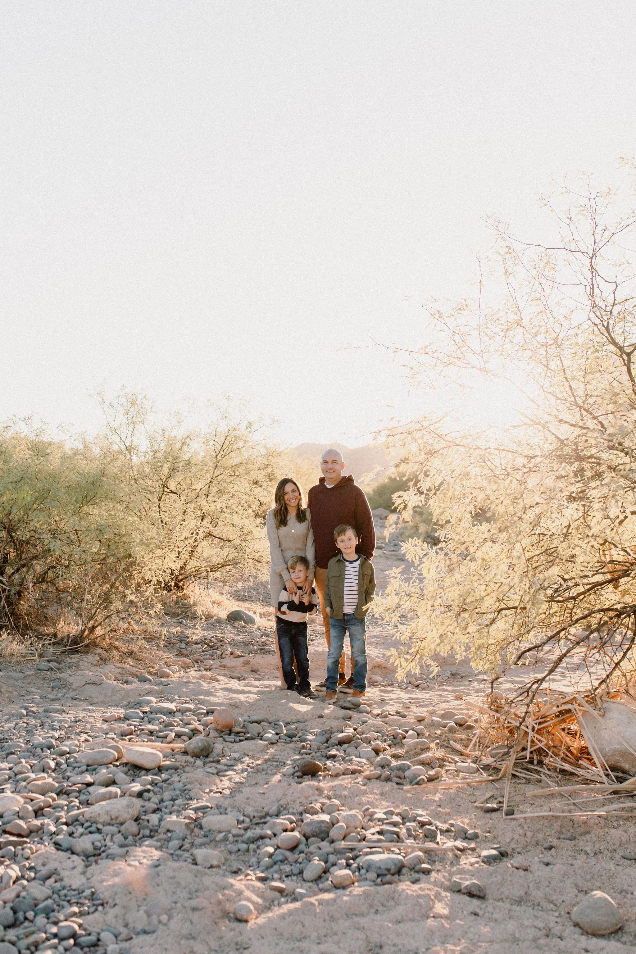 family standing together and smiling in desert golden hour photography session at the Salt River in Arizona