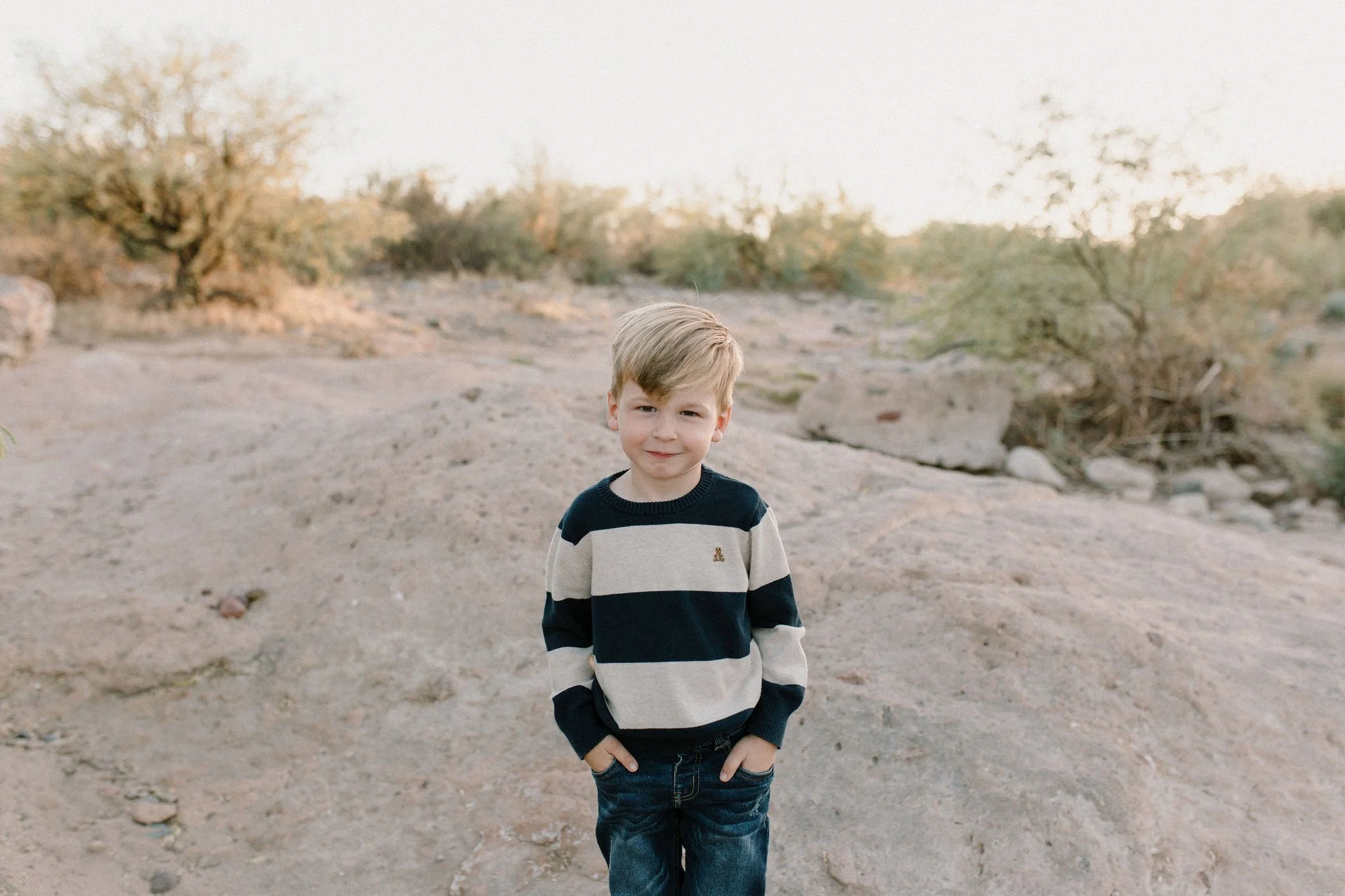 son standing and smiling in desert family photography session at the Salt River in Arizona