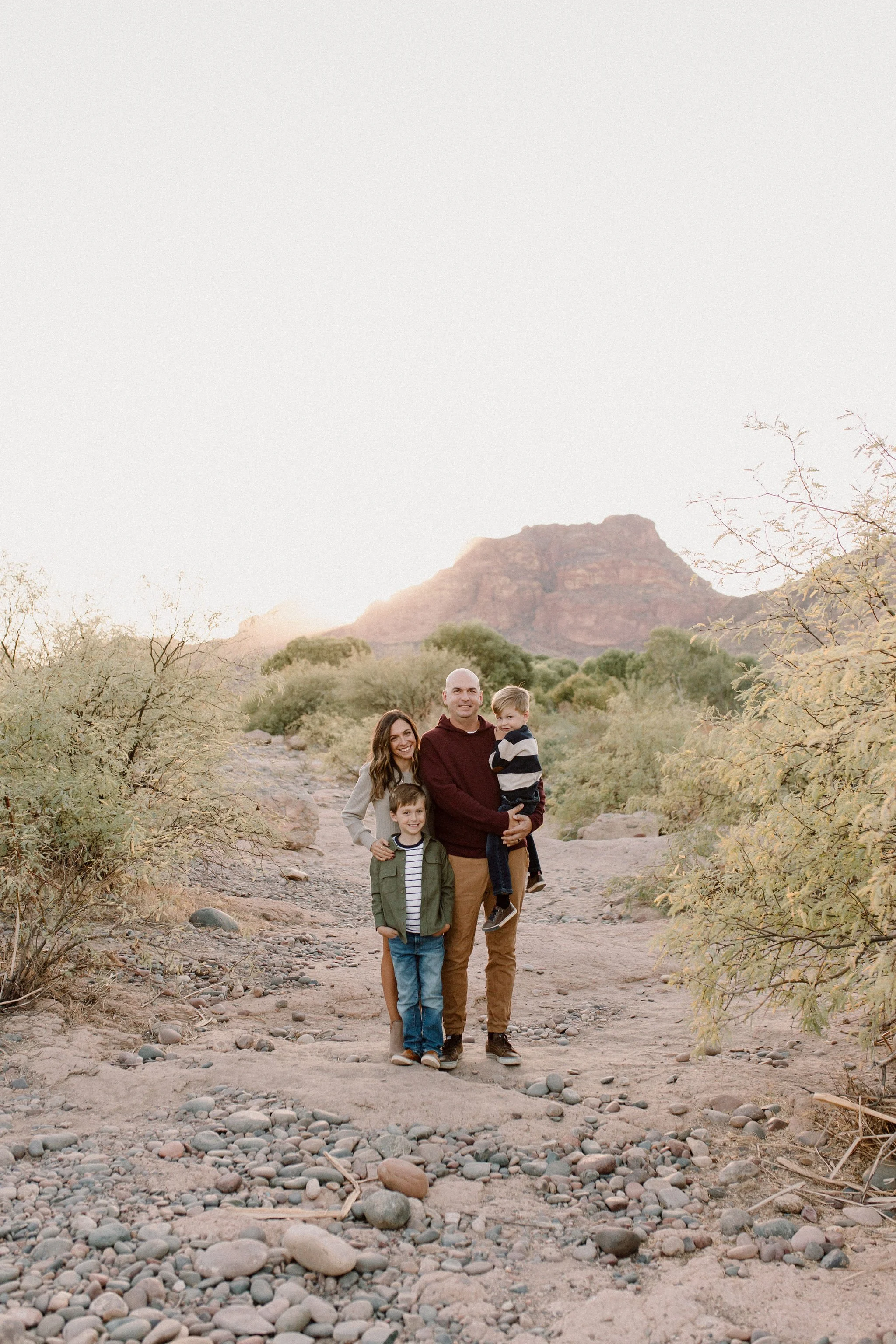 Family standing together in the desert with mountain behind them smiling at the camera