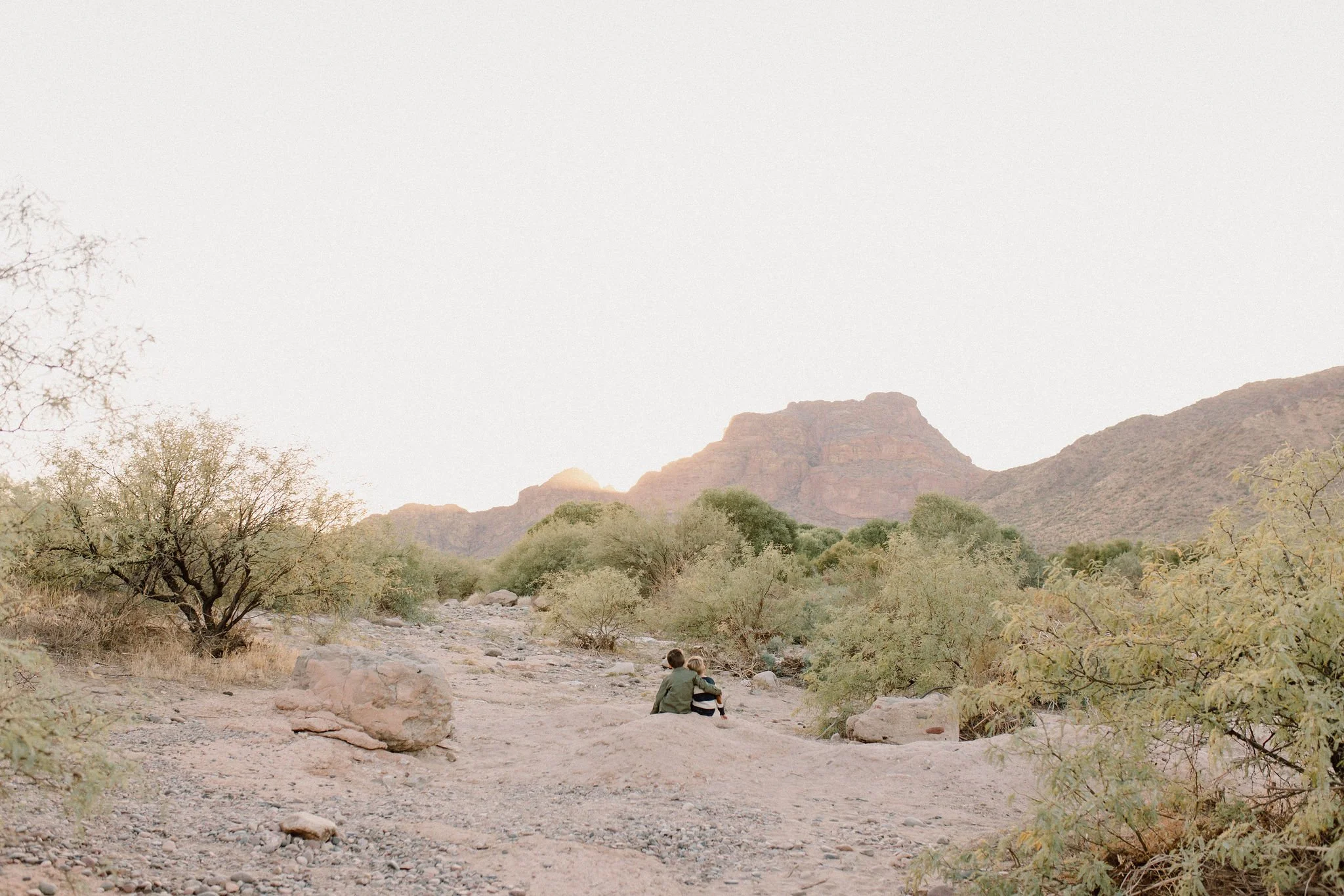brothers sitting together in the desert looking at Red Mountain at the Salt River in Arizona