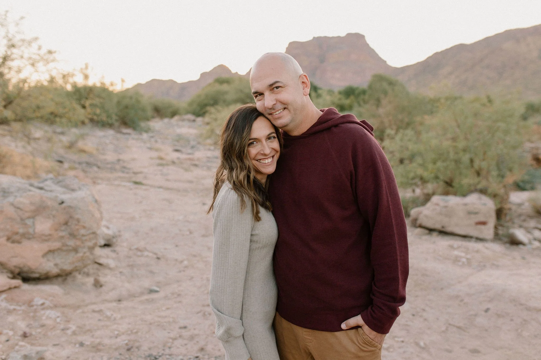 mom and dad standing together and smiling in desert by the Salt River in Arizona