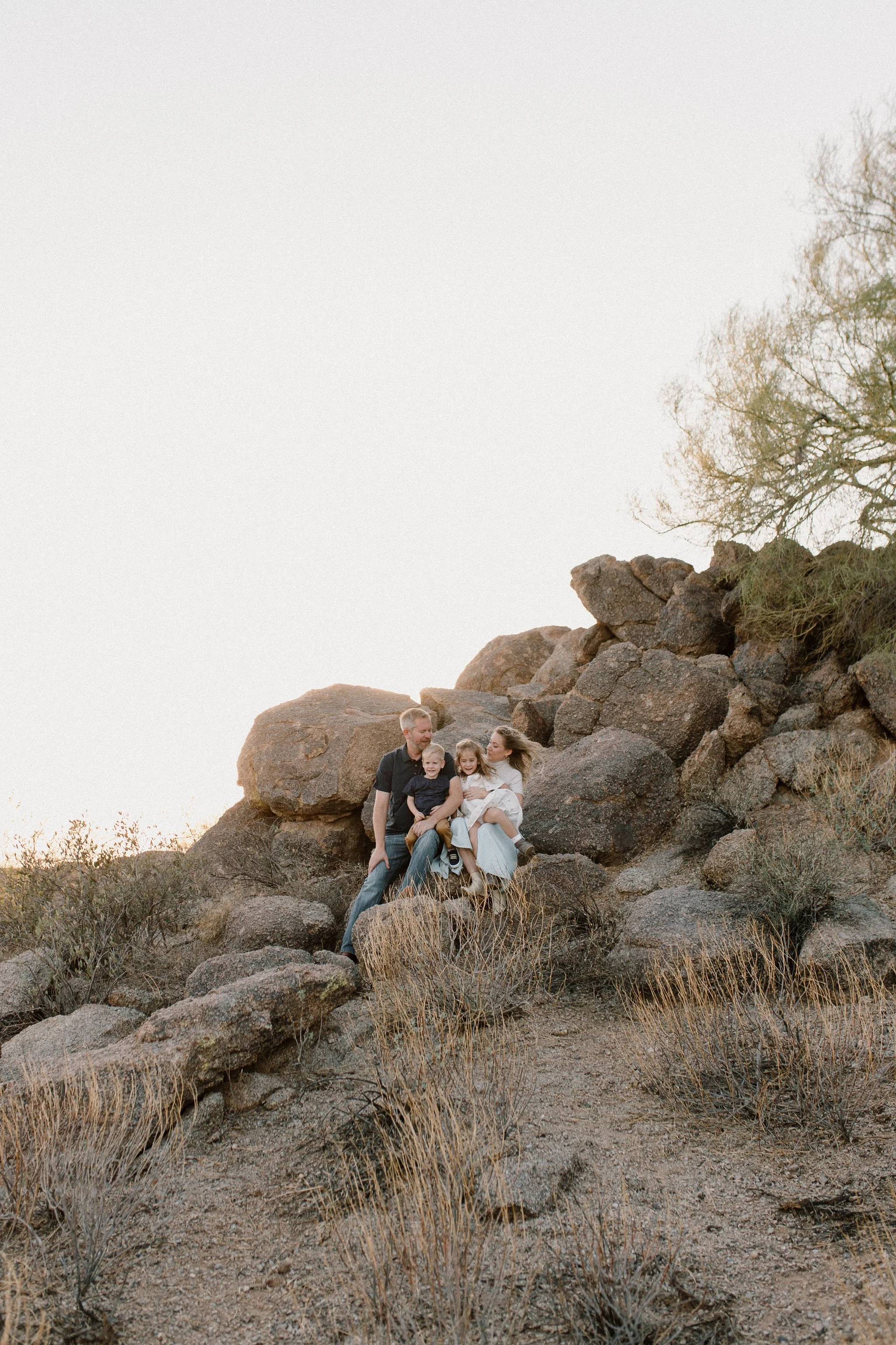 family sitting together on boulders in the desert during windy family photo session