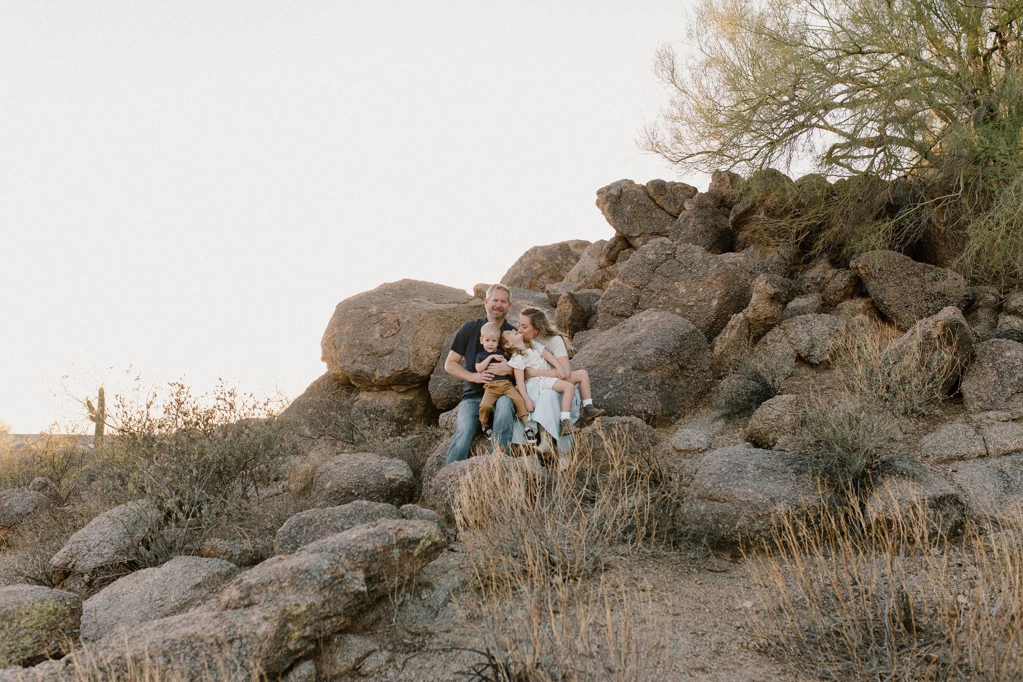 family sitting and smiling on boulders in desert family photography session