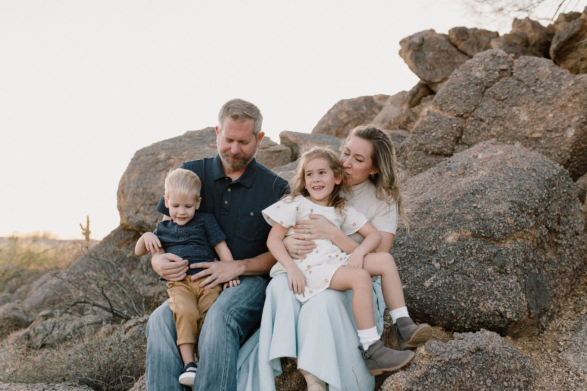 family sitting on boulders in desert windy family photo session