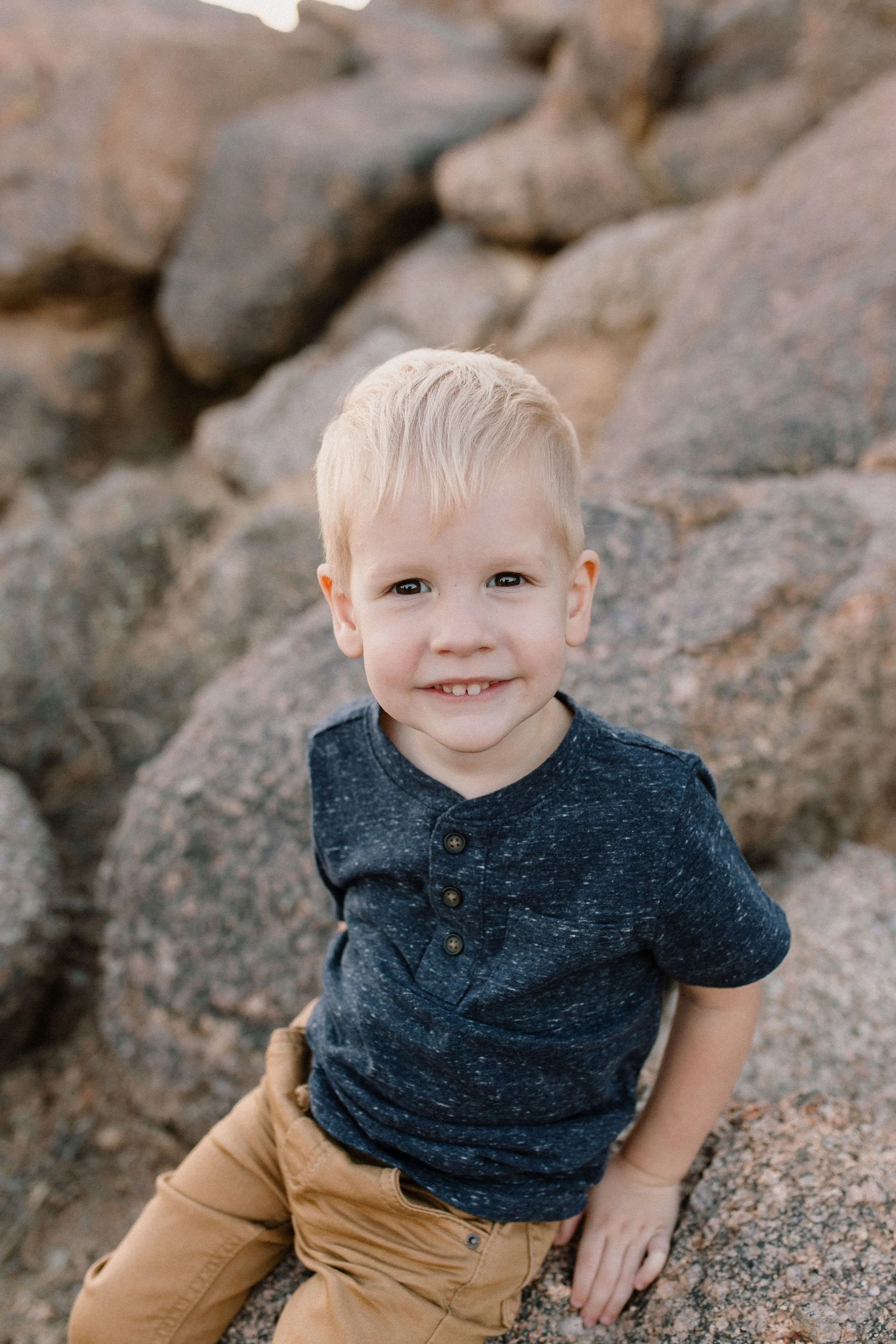 toddler sitting on boulder in windy desert family photo session