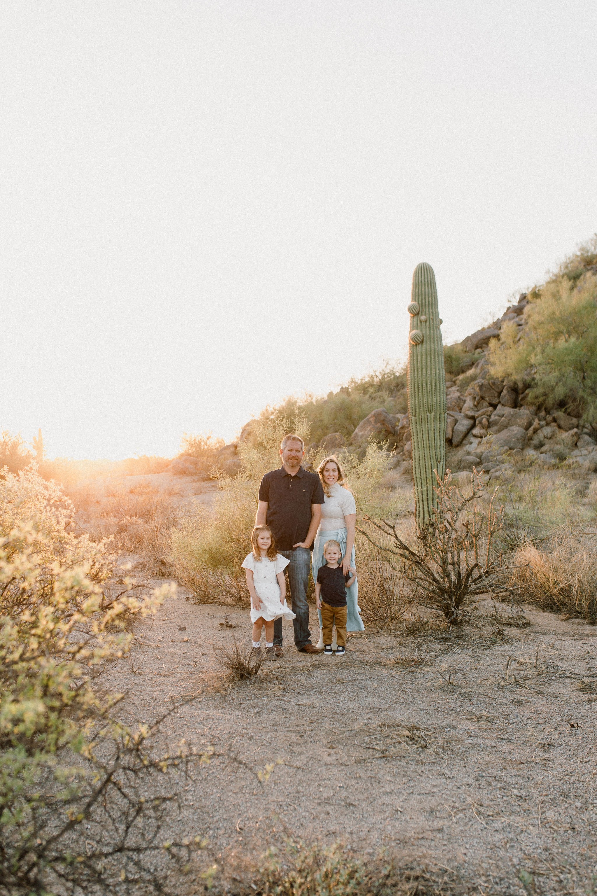 family standing together and smiling in windy desert family photo session