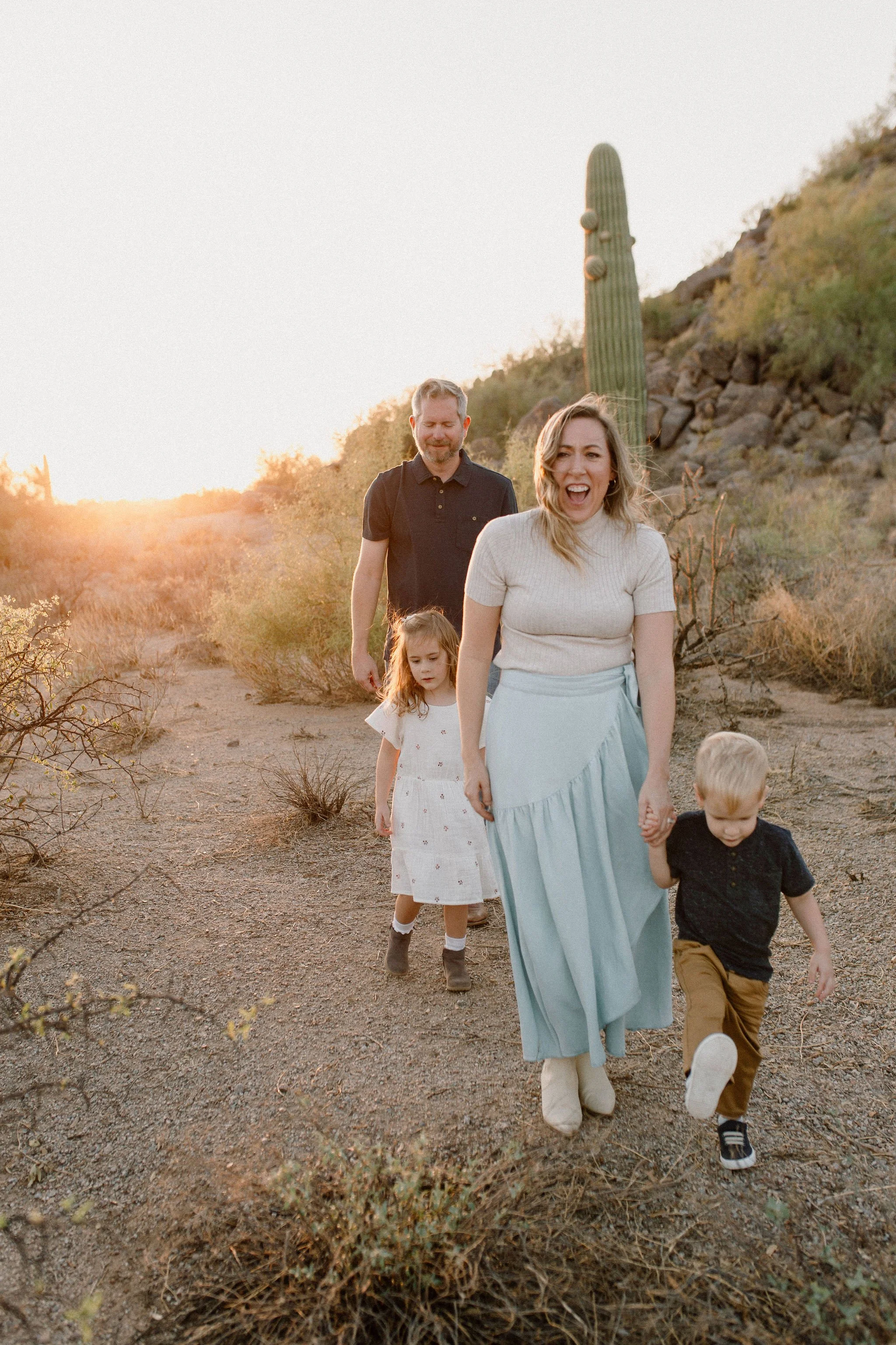 family walking and holding hands in the desert during windy family photo session