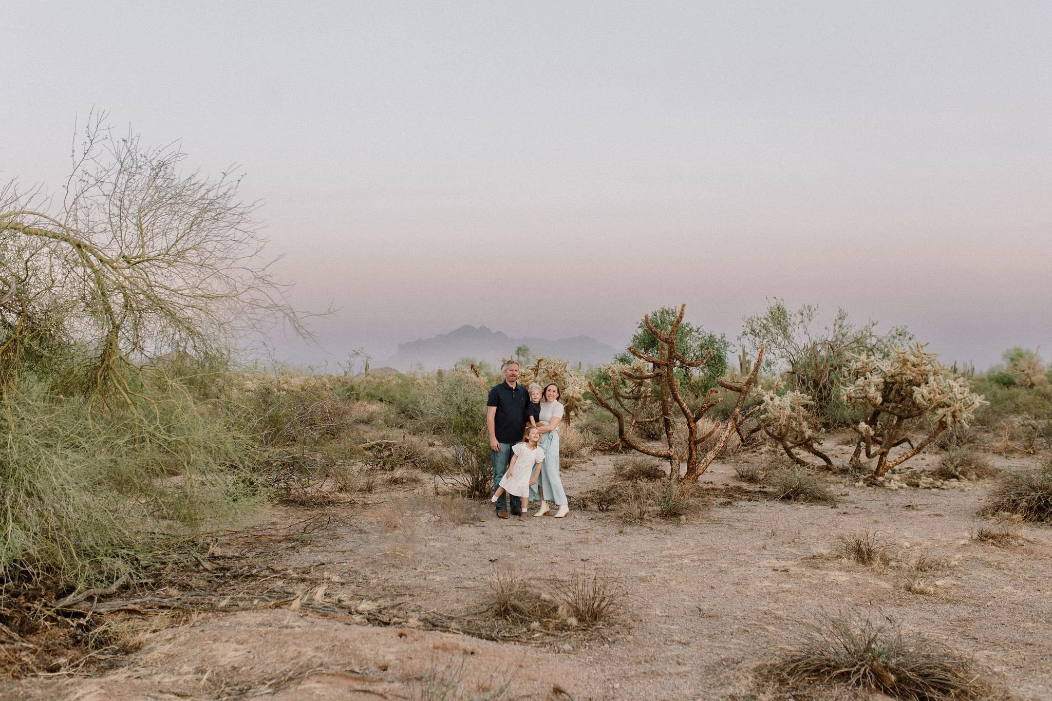 family standing together smiling in the desert during blue hour with the Superstition Mountains in the background of family photography session