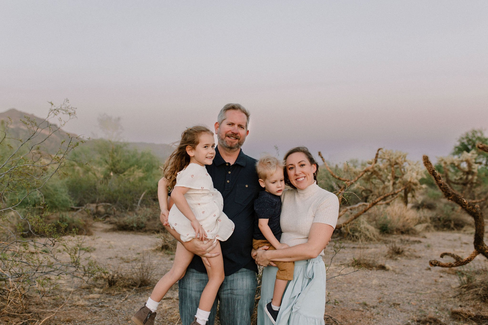 parents holding toddlers in the desert during blue hour windy family photo session