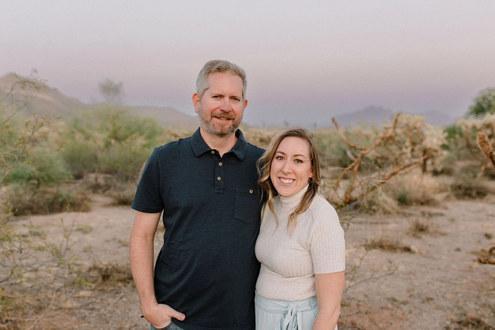 mom and dad standing and smiling during blue hour during windy family photo session
