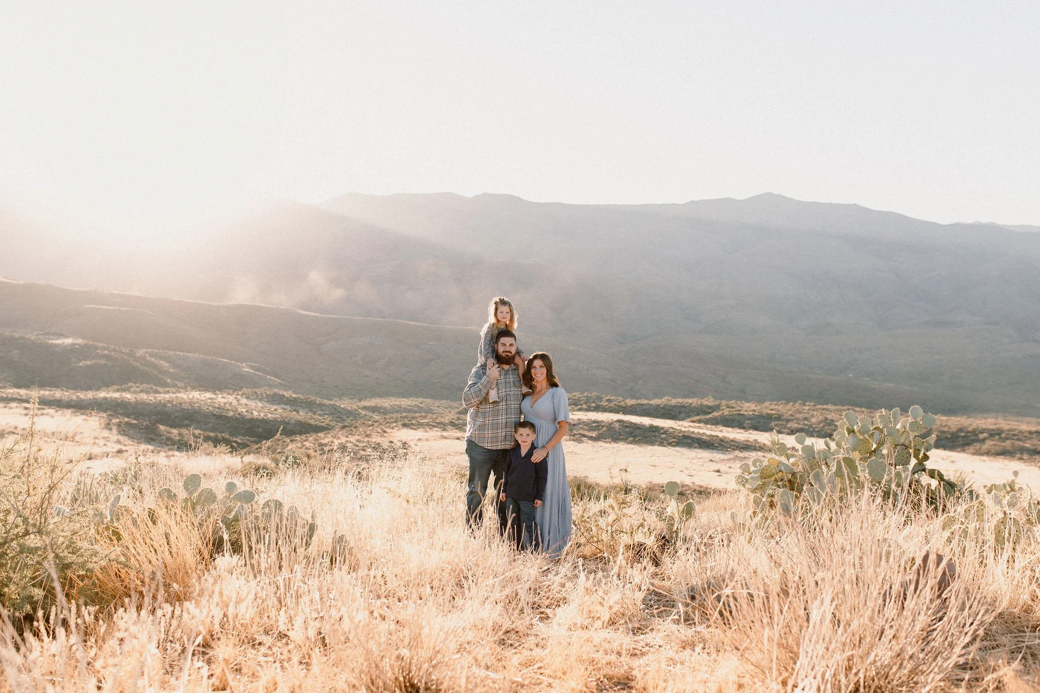 family standing together in front of mountains in golden hour light photoshoot in Arizona